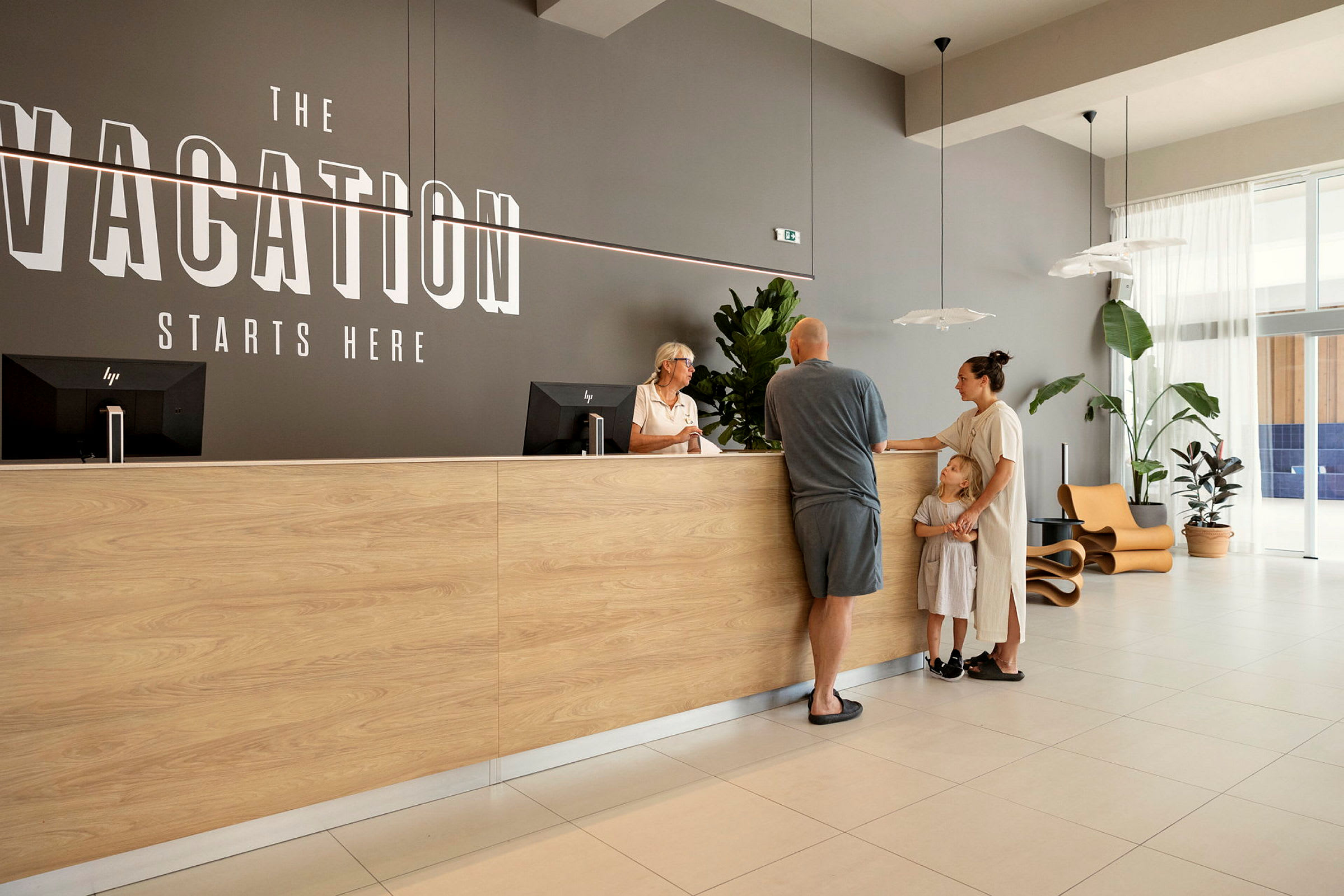 En resepsjon med en trebord og teksten "Vacation Starts Here" på veggen. (AI-generert tekst)