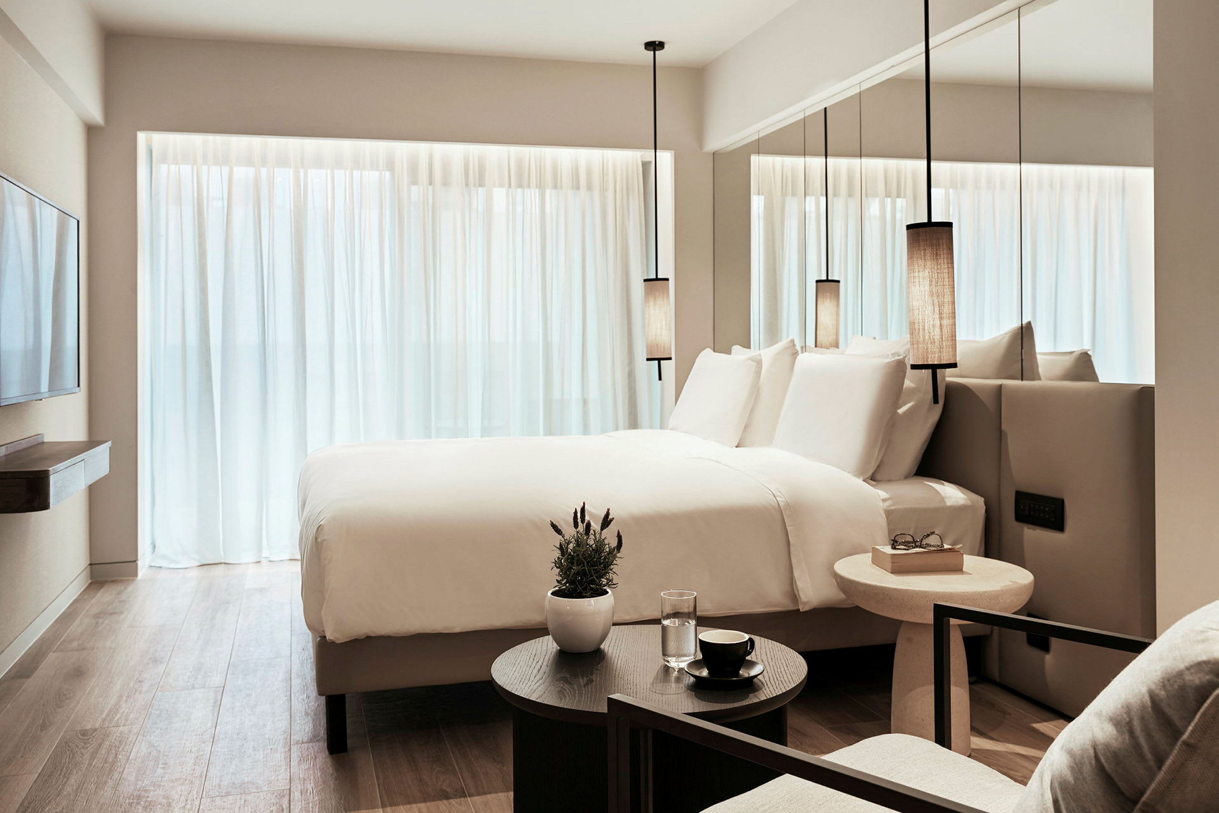 Et moderne hotellrom med en stor seng, hvite laken og minimalistisk innredning. (AI-generert tekst)