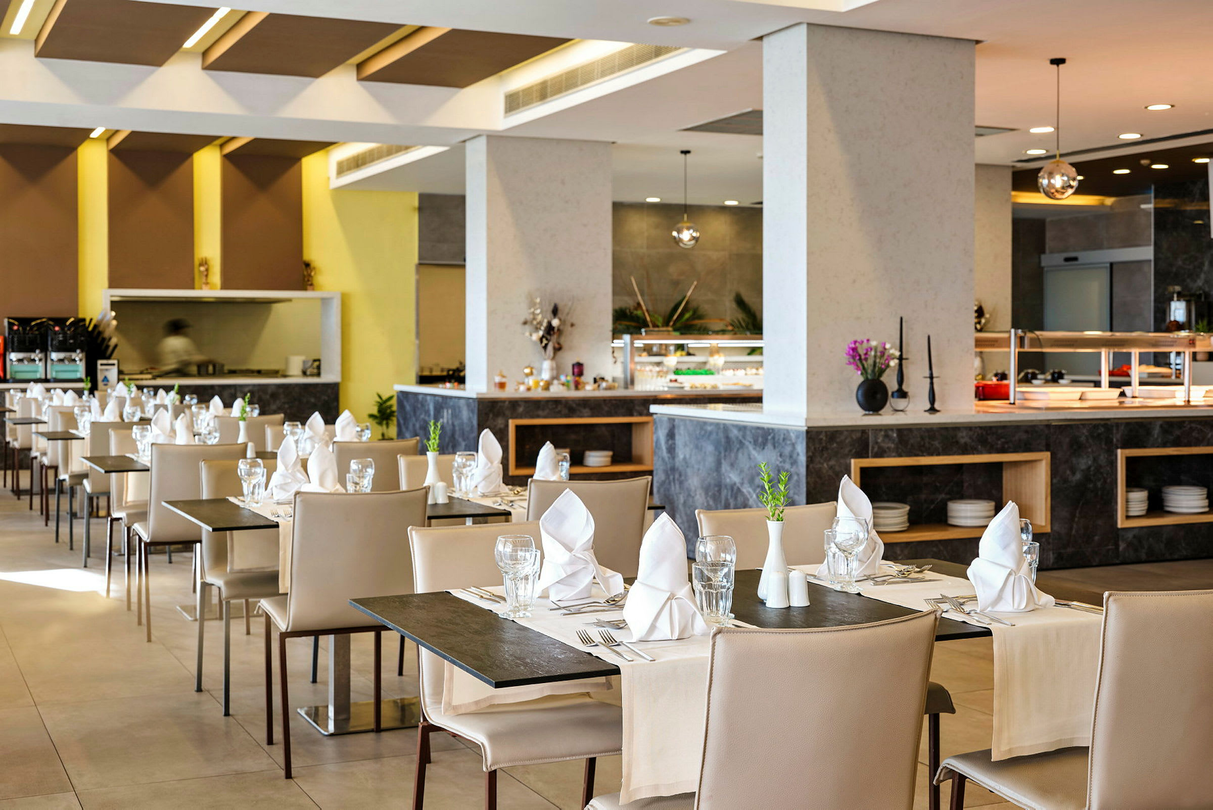 En moderne restaurant med dekkede bord, beige stoler og servietter på hvert bord. (AI-generert tekst)