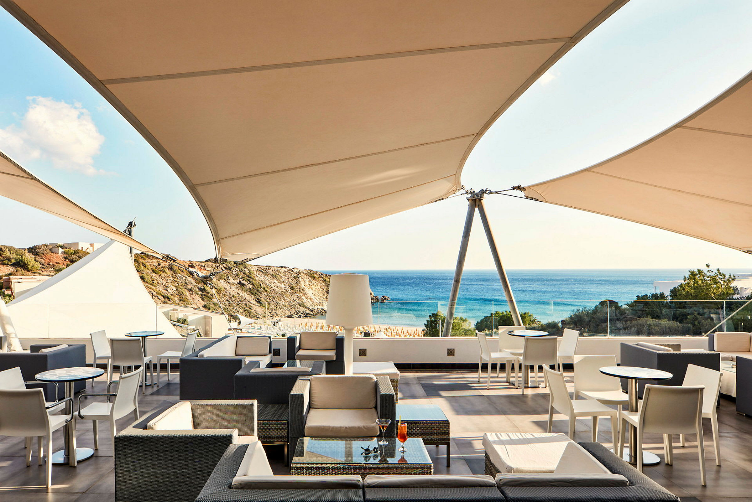 Terrasse med sittemøbler og parasoller, utsikt mot havet. (AI-generert tekst)