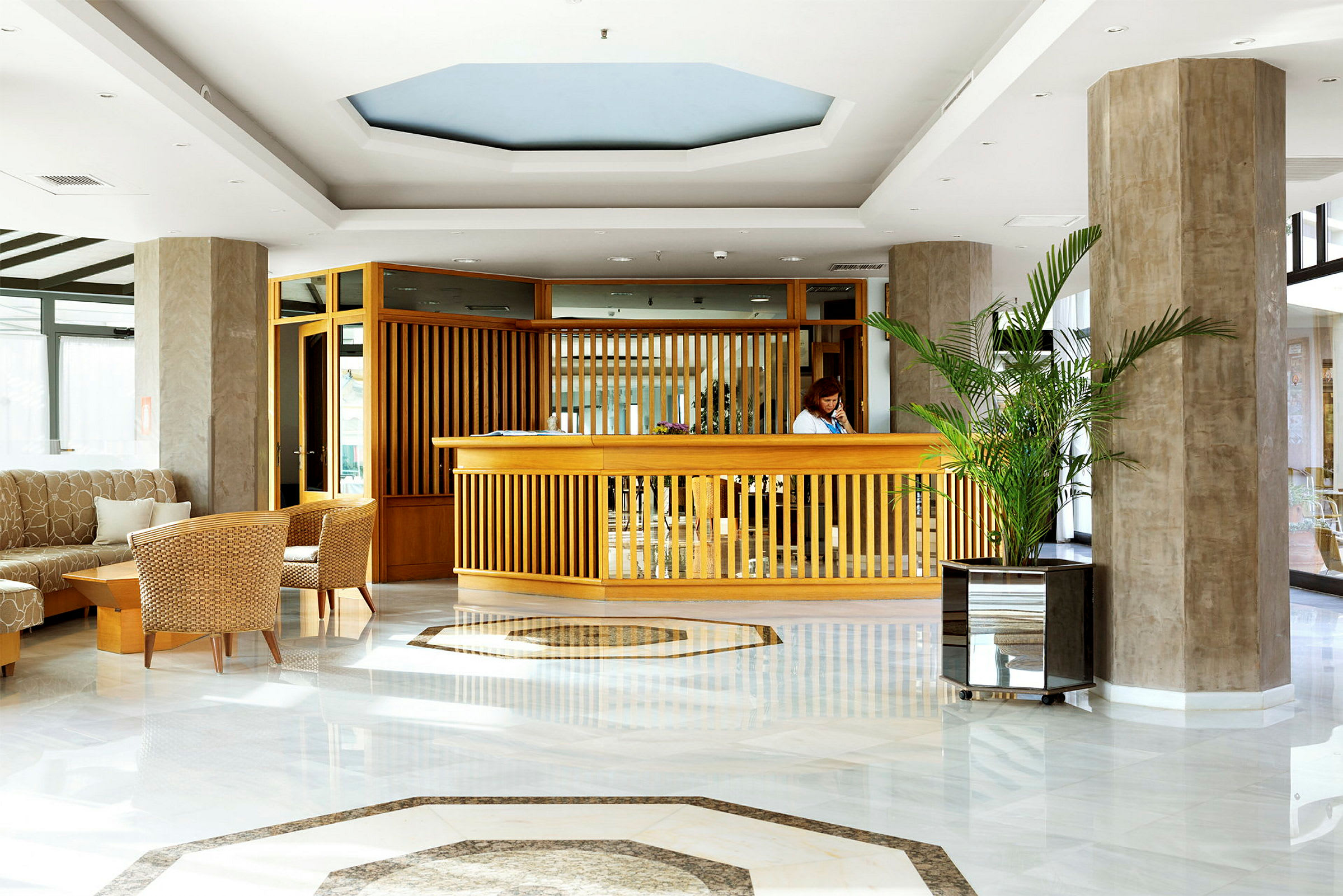 Resepsjon i hotellobby med treinteriør og planter. (AI-generert tekst)