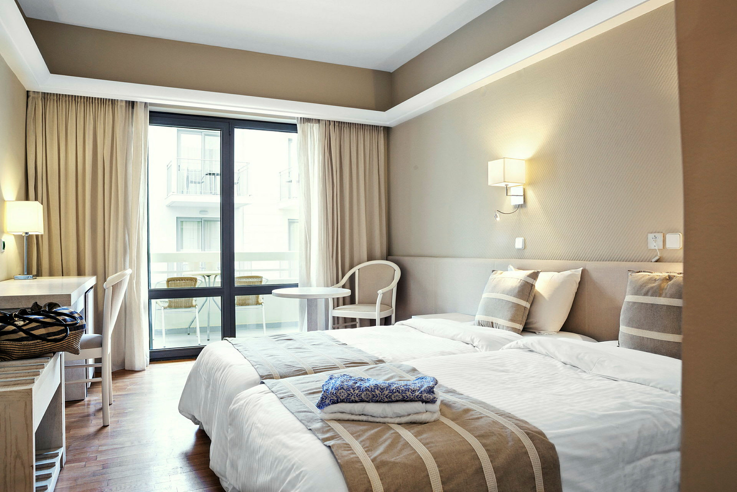 Hotellrom med to enkeltsenger, skrivebord og balkong. (AI-generert tekst)