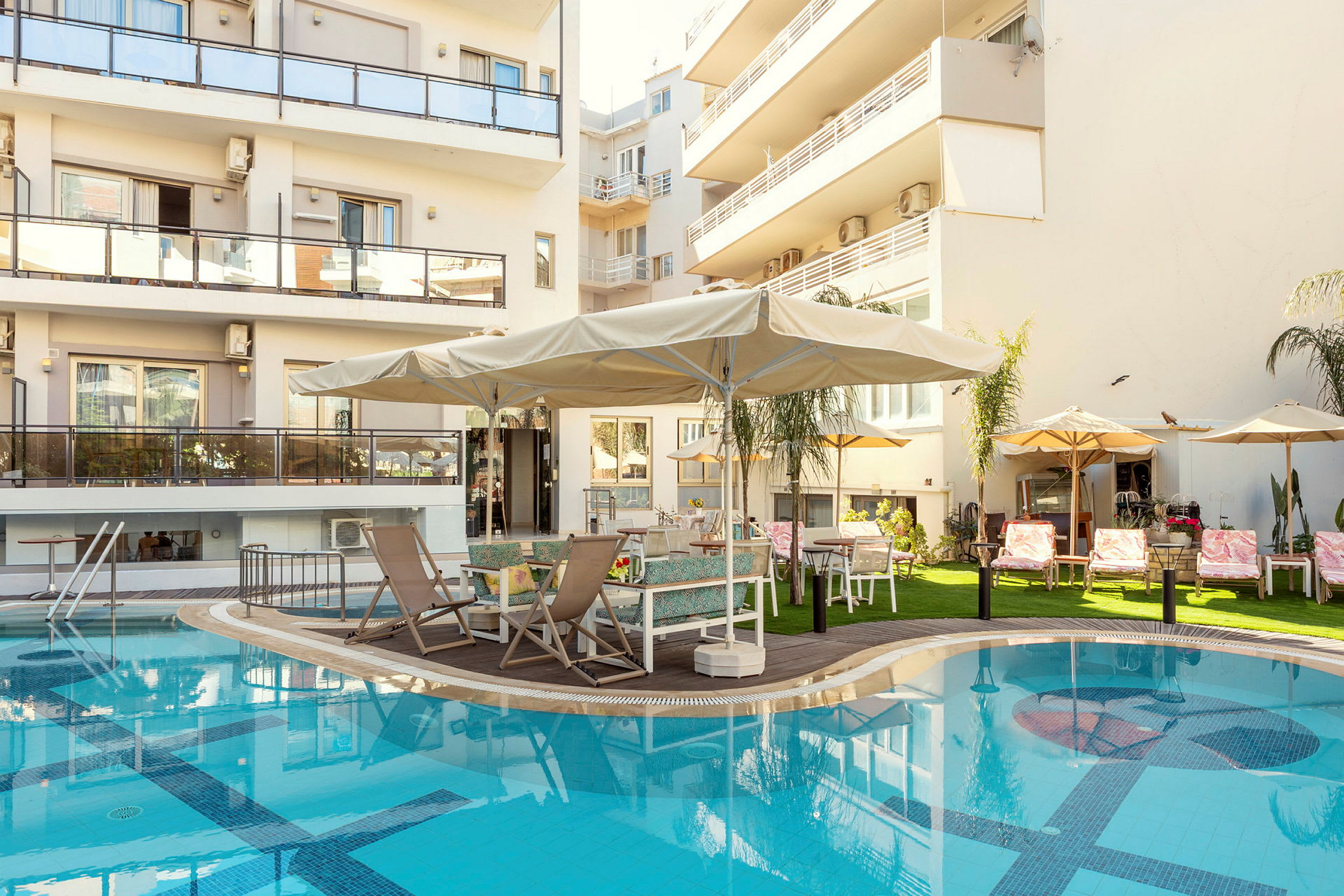 Bilde av en bygning med balkonger, et svømmebasseng og en terrasse med solsenger og parasoller. (AI-generert tekst)