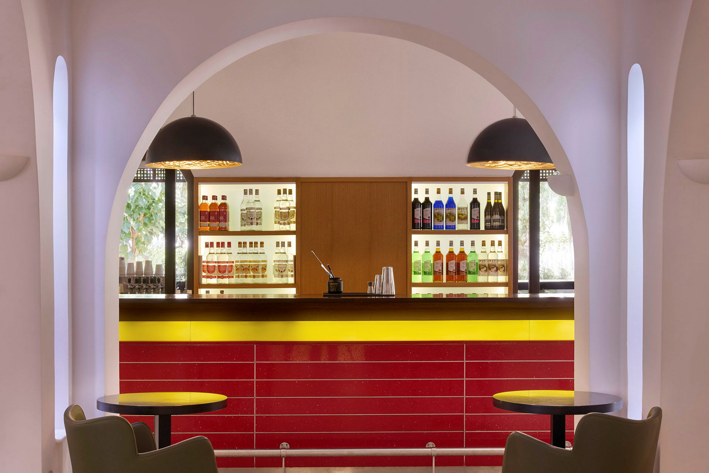 Bilde av en bar med flasker plassert på hyller, sitteplasser og buet arkitektur. (AI-generert tekst)