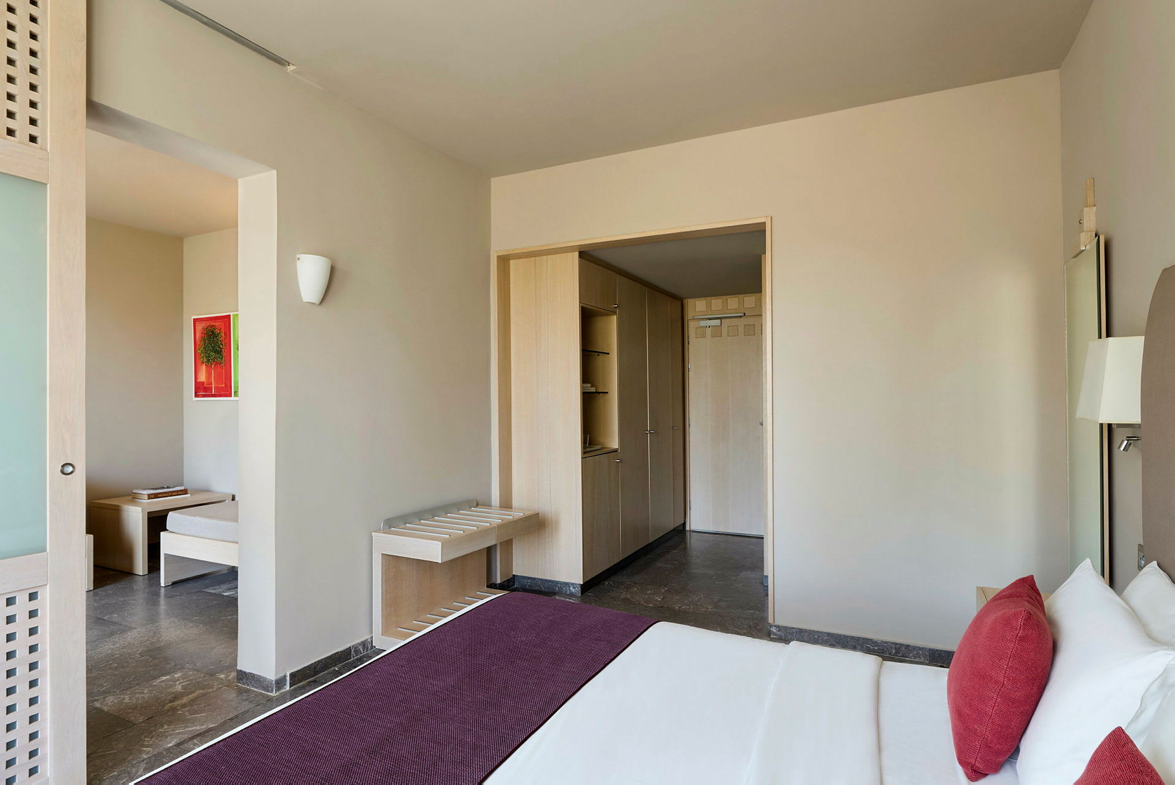 Et hotellrom med en seng, et skap og en sitteplass. (AI-generert tekst)