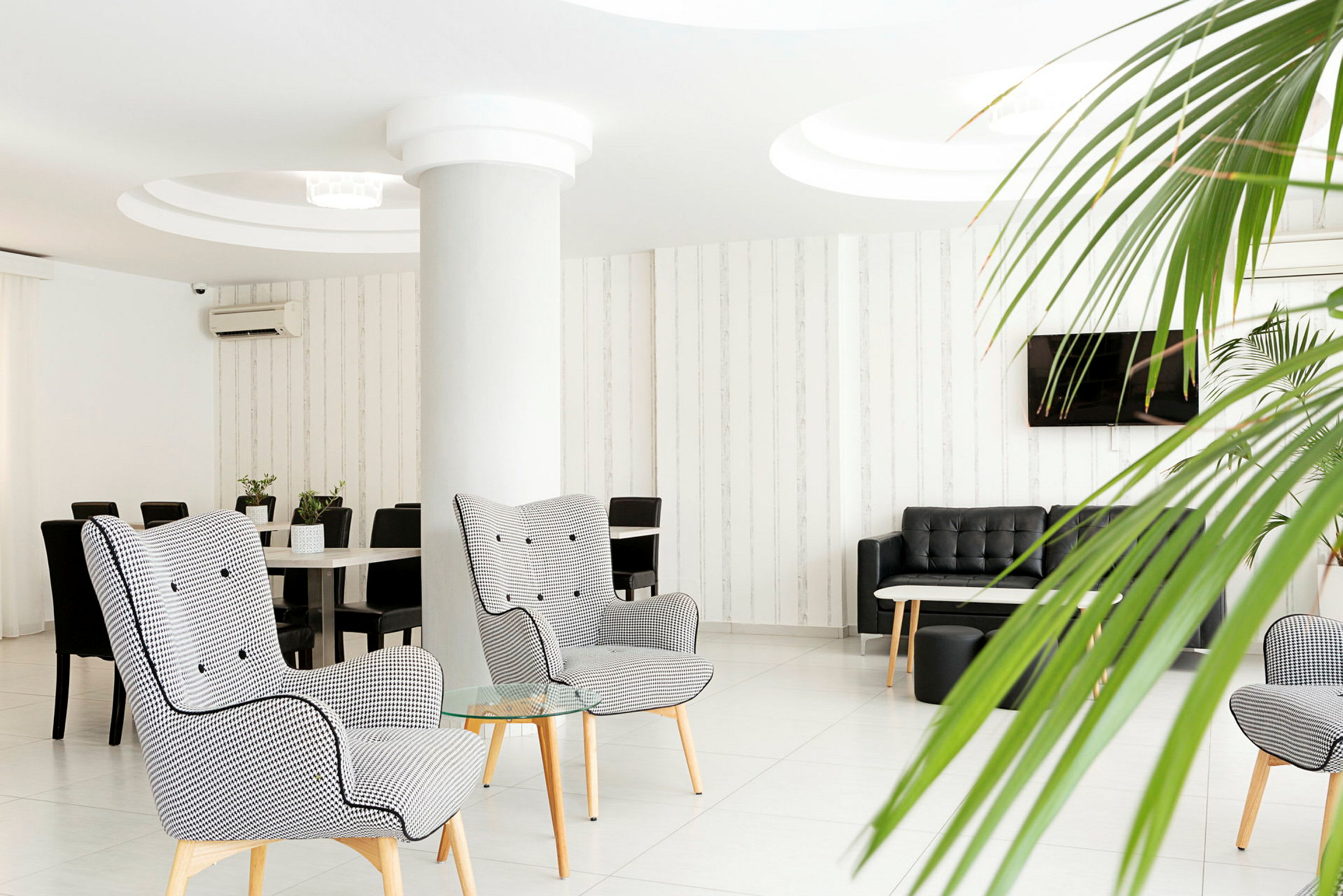 Moderne hotellsalong med lenestoler, sofaer og plantepynt. (AI-generert tekst)