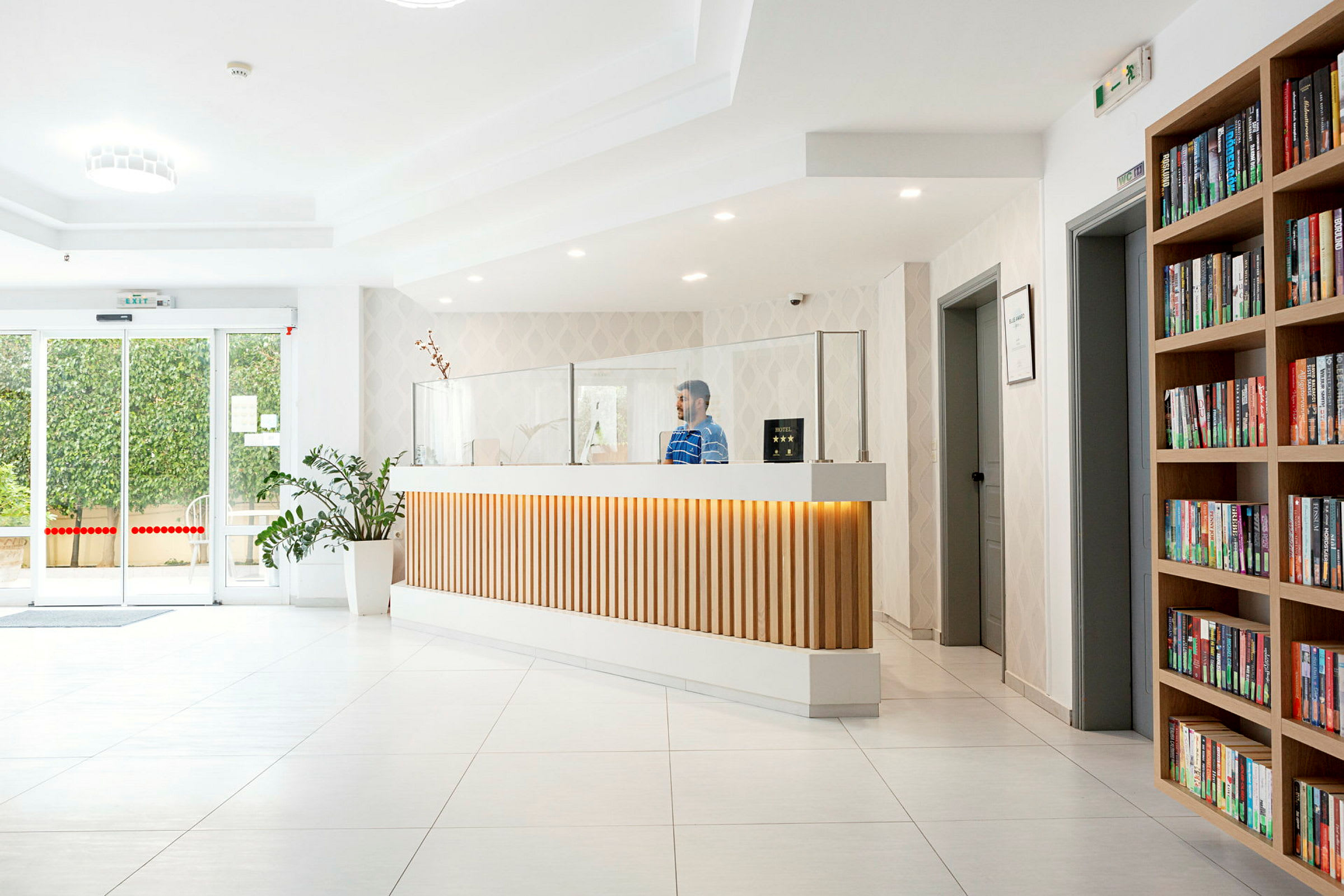 Moderne hotellresepsjon med bokhylle og plante. (AI-generert tekst)