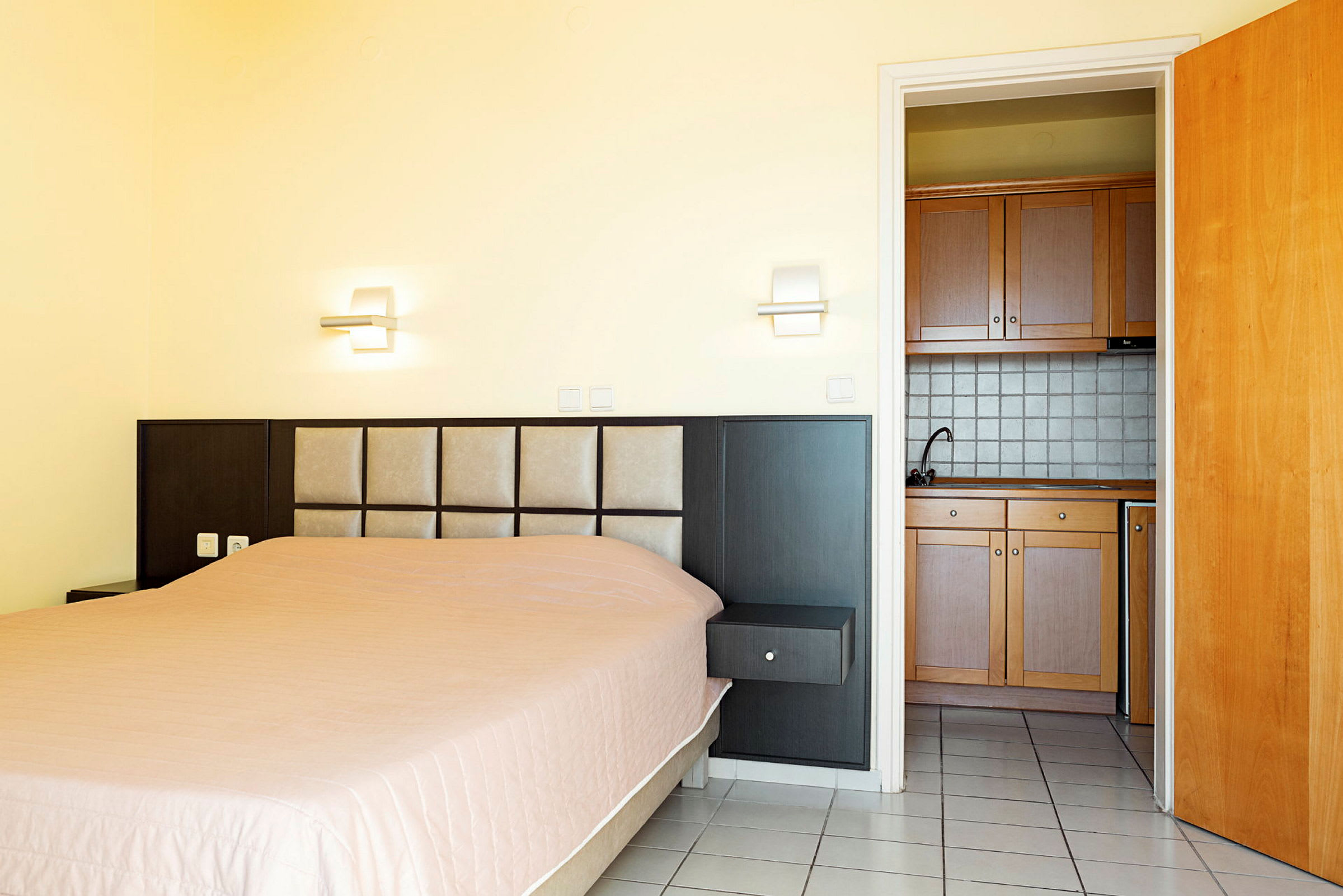 Hotellrom med seng og minikjøkken. (AI-generert tekst)