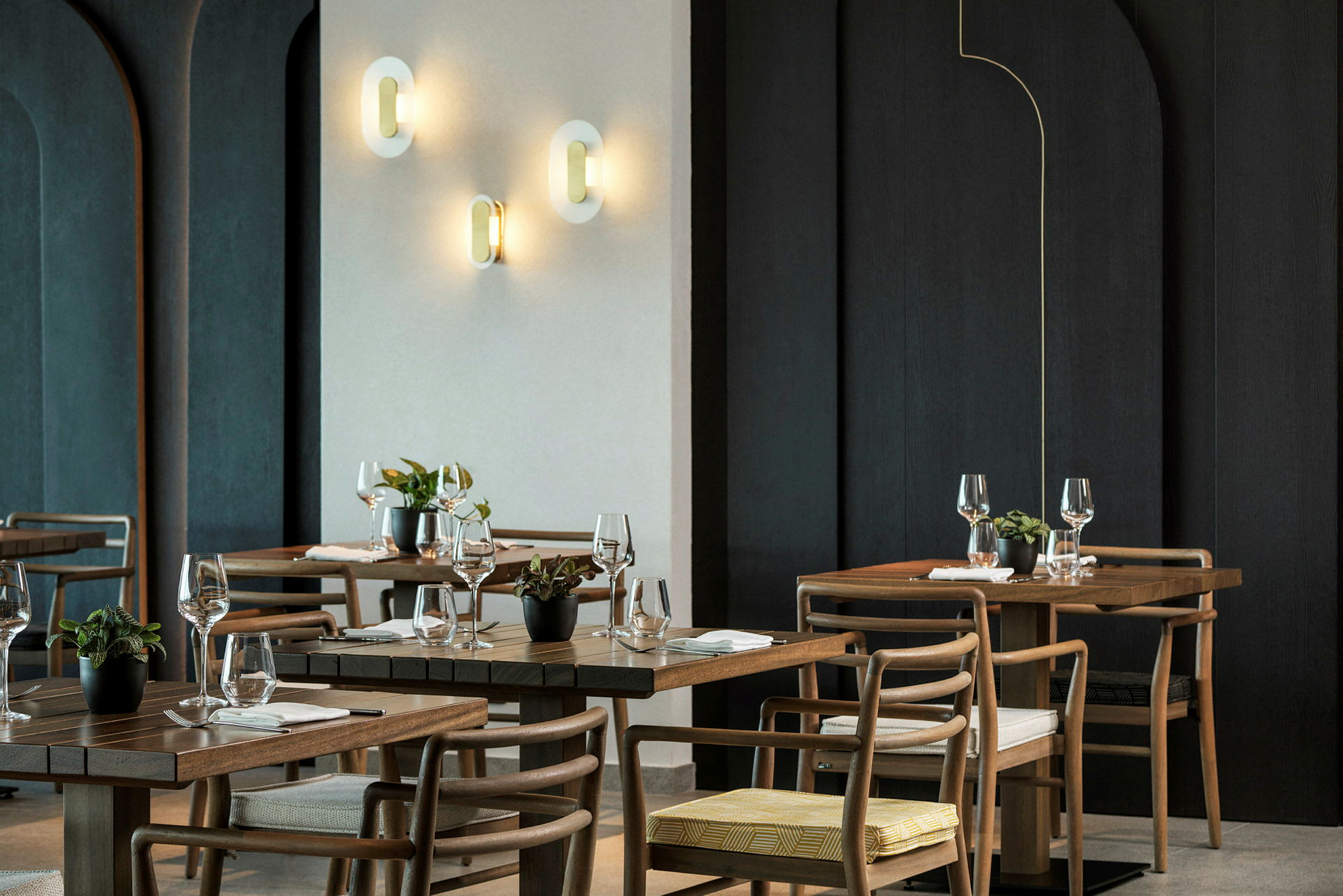 En elegant restaurant med trebord, stoler og veggbelysning. (AI-generert tekst)
