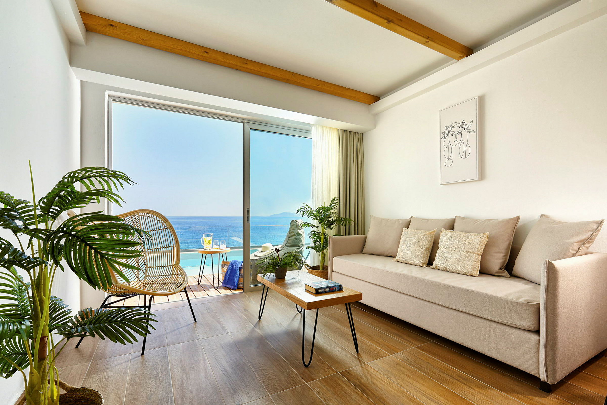 Lyst rom med sofa, trebord og planter, med utsikt over havet fra den tilstøtende balkongen. (AI-generert tekst)