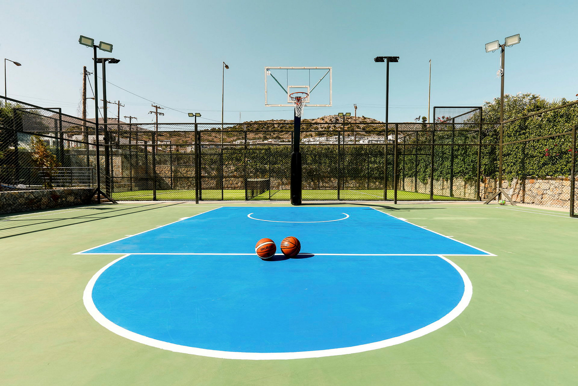 En basketballbane med blå markeringer og to basketballer plassert i midten. (AI-generert tekst)