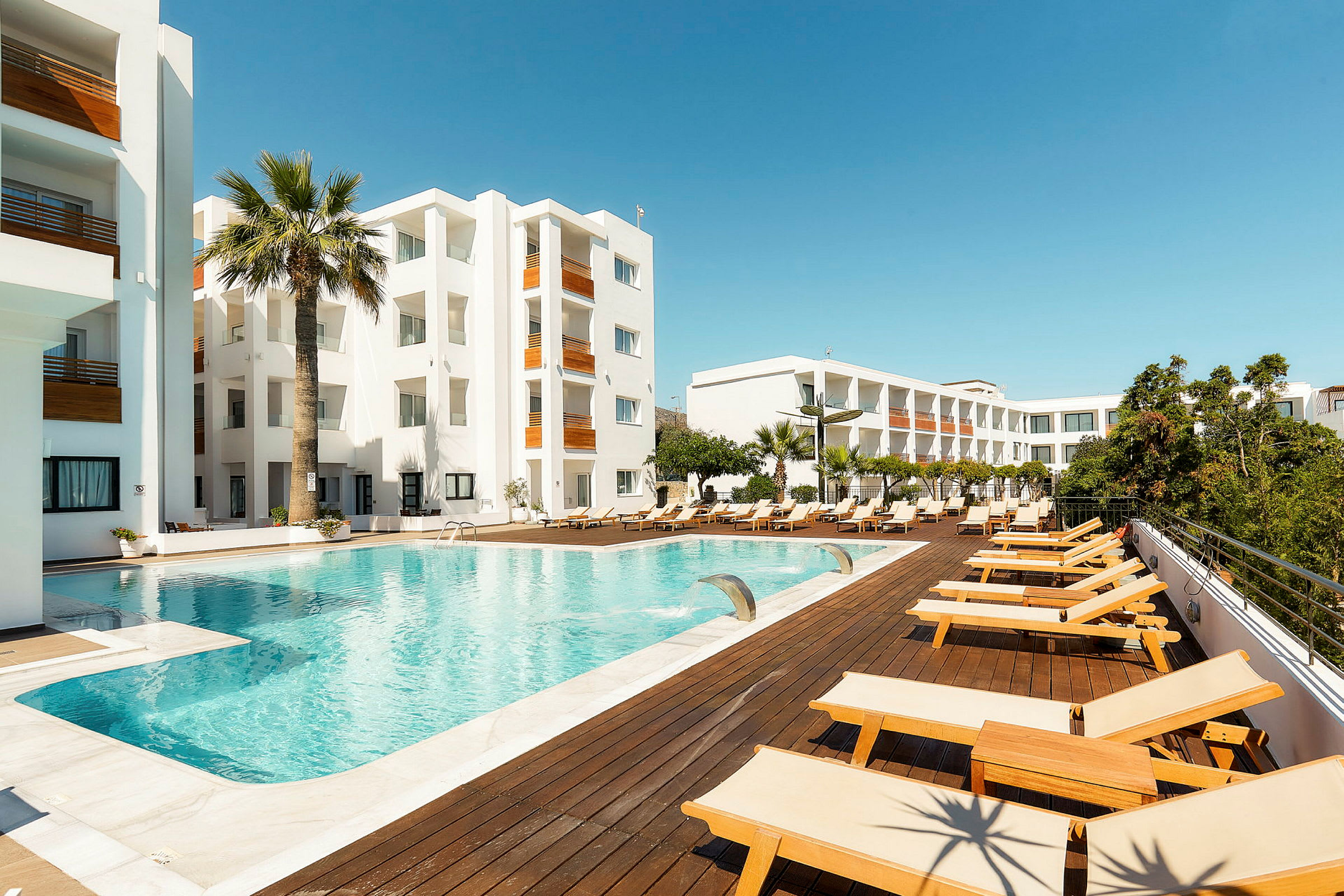 Hotellområde med svømmebasseng og solsenger. (AI-generert tekst)