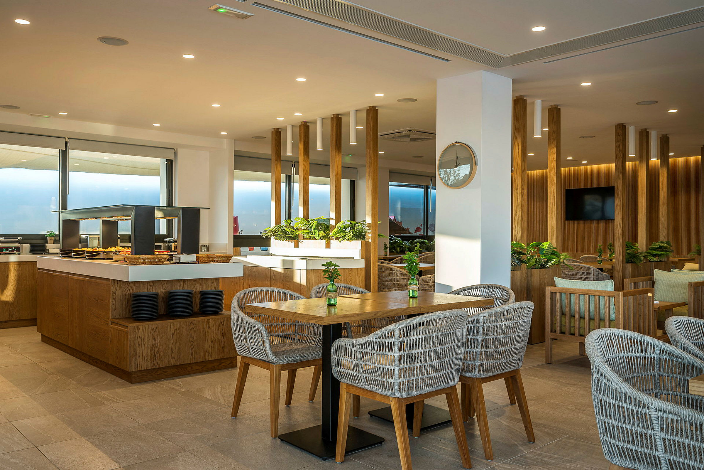 Bilde av en hotellrestaurant med moderne møbler og innendørs planter. (AI-generert tekst)