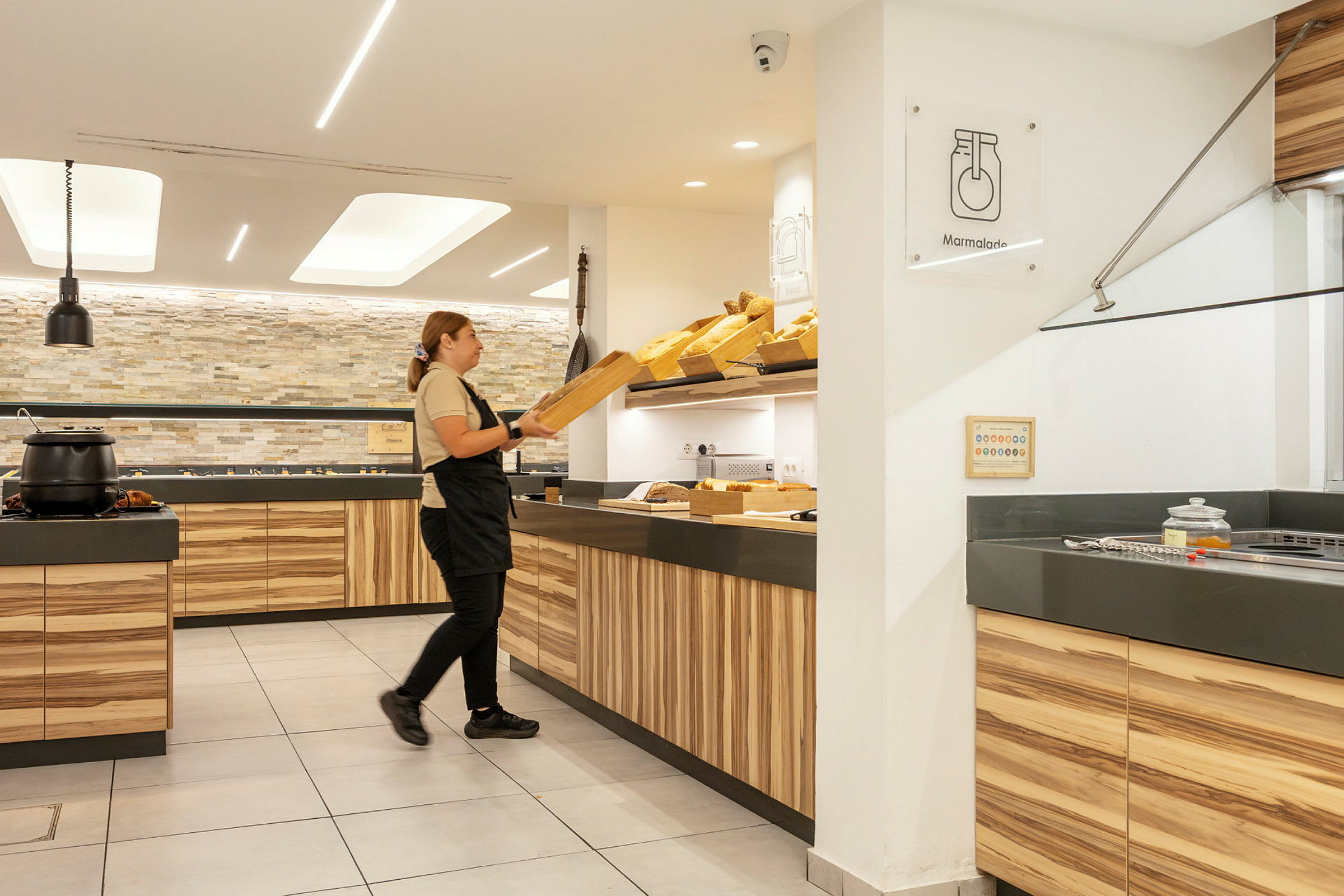 En person organiserer brød i et lyst og moderne serveringsområde. (AI-generert tekst)