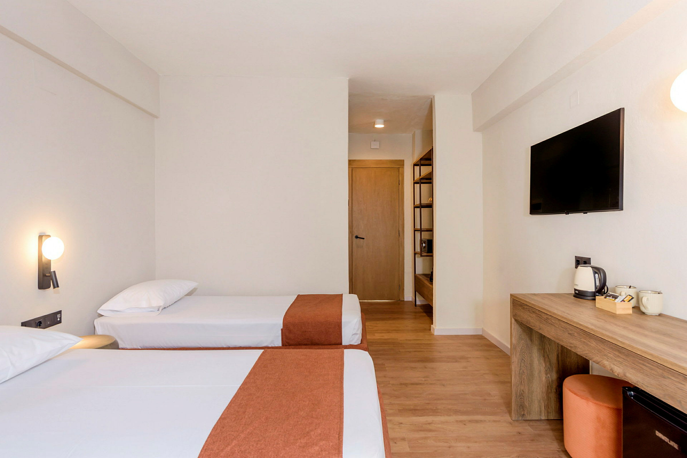 To enkeltsenger på et hotellrom, med et skrivebordsområde og TV på veggen. (AI-generert tekst)