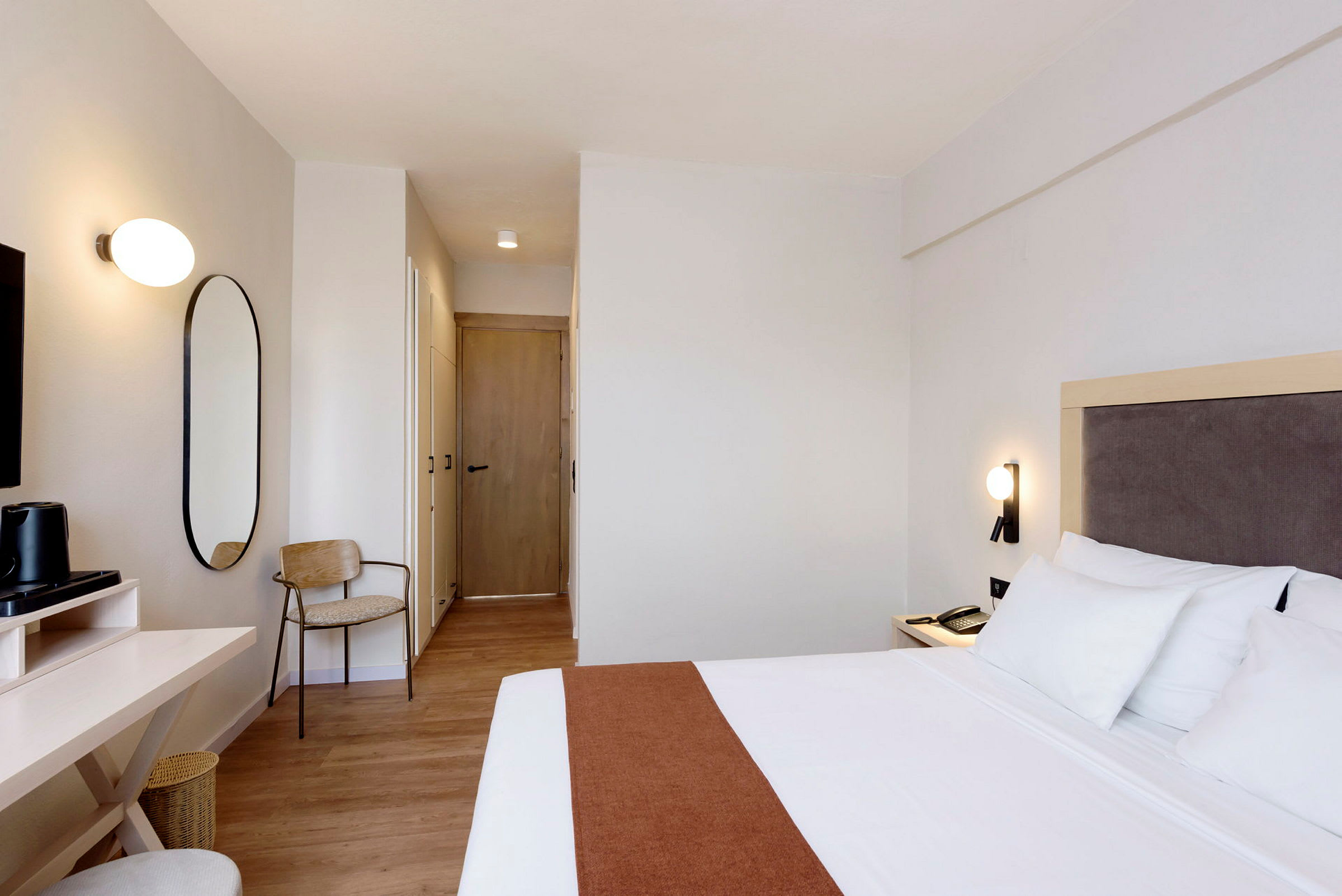 Et hotellrom med en seng, skrivebord og stol. (AI-generert tekst)
