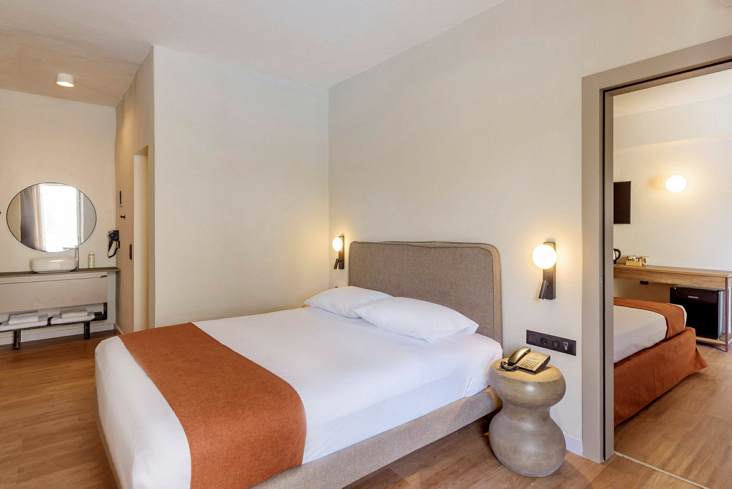 Et hotellrom med en dobbeltseng, et nattbord og et speil over en vask. (AI-generert tekst)