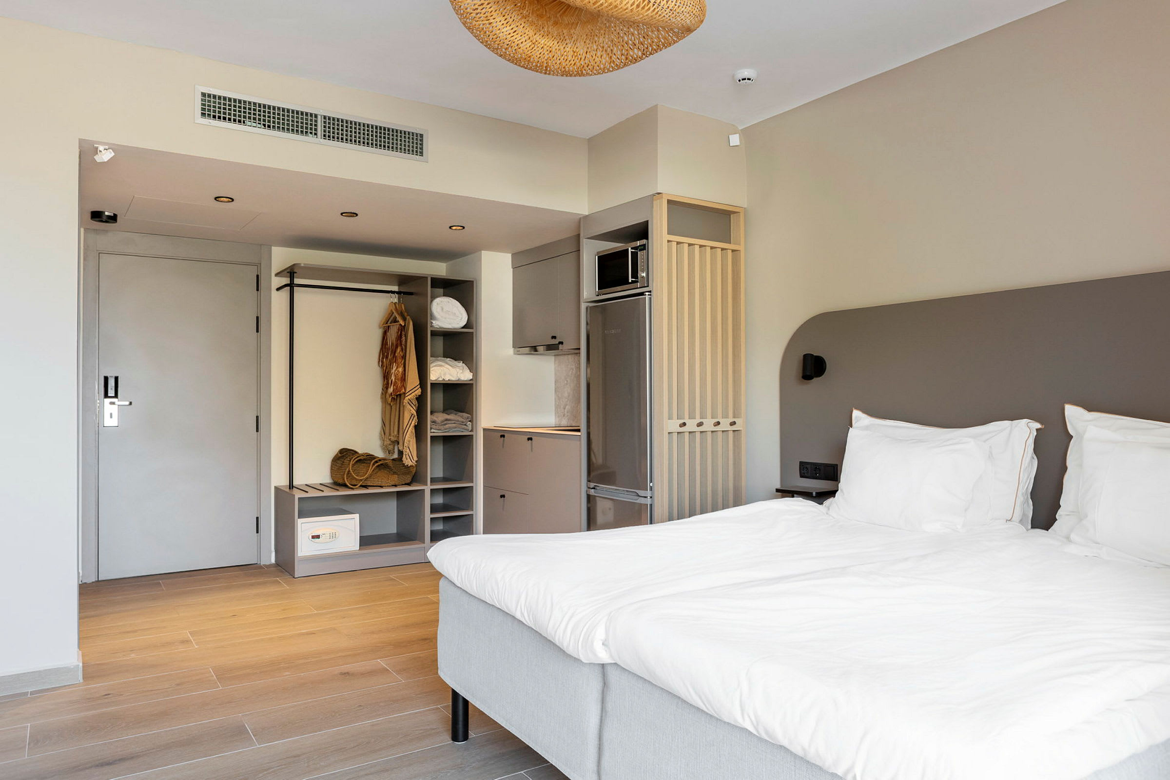 Et hotellrom med en dobbeltseng, garderobe og kjøkkenutstyr. (AI-generert tekst)