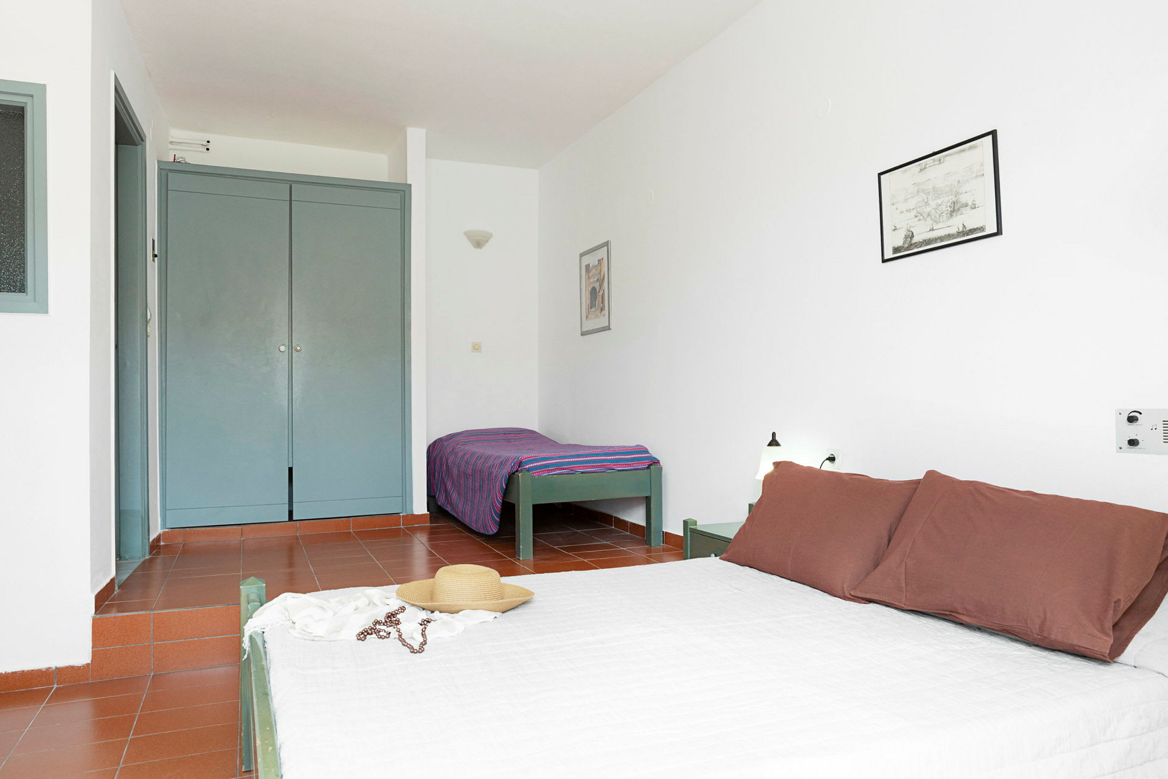 Et hotellrom med en dobbeltseng og enkeltseng, garderobe og minimalistisk innredning. (AI-generert tekst)