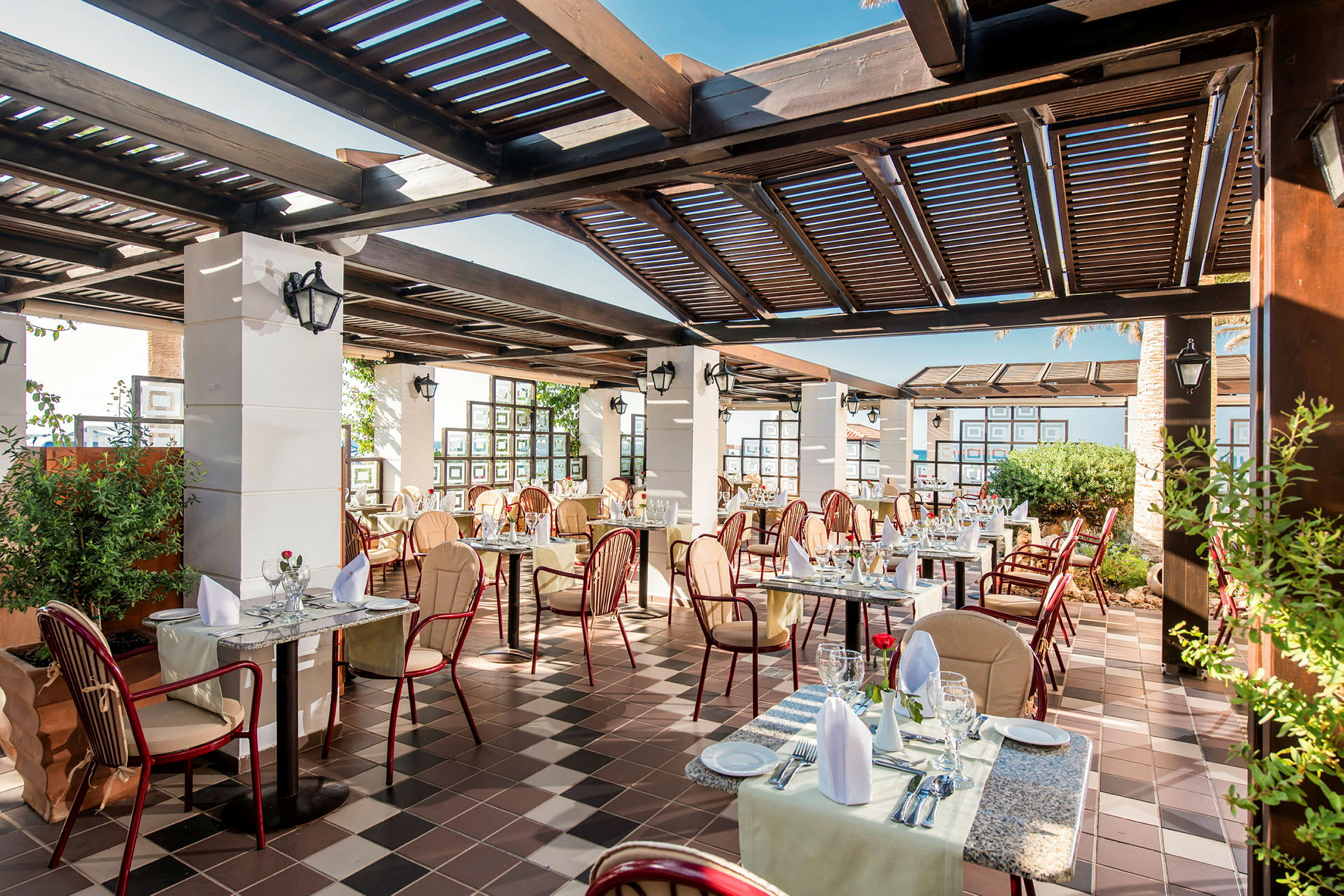 En utendørs restaurant med dekkede bord og stoler under en pergola. (AI-generert tekst)