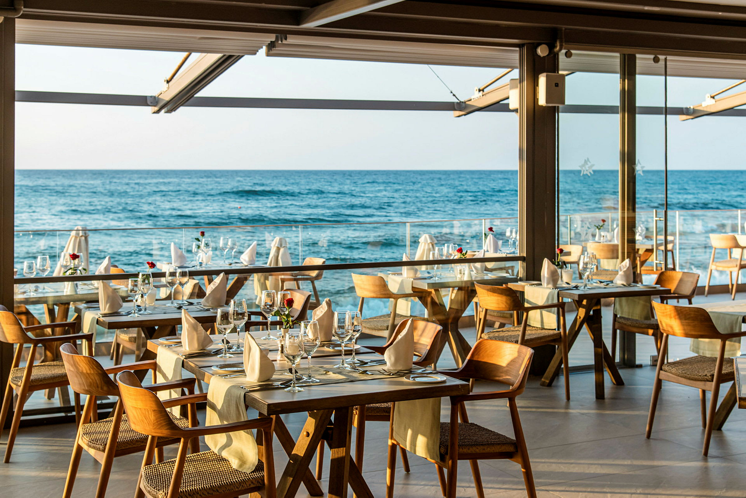Bilde av en restaurant med dekkede bord og utsikt over havet. (AI-generert tekst)