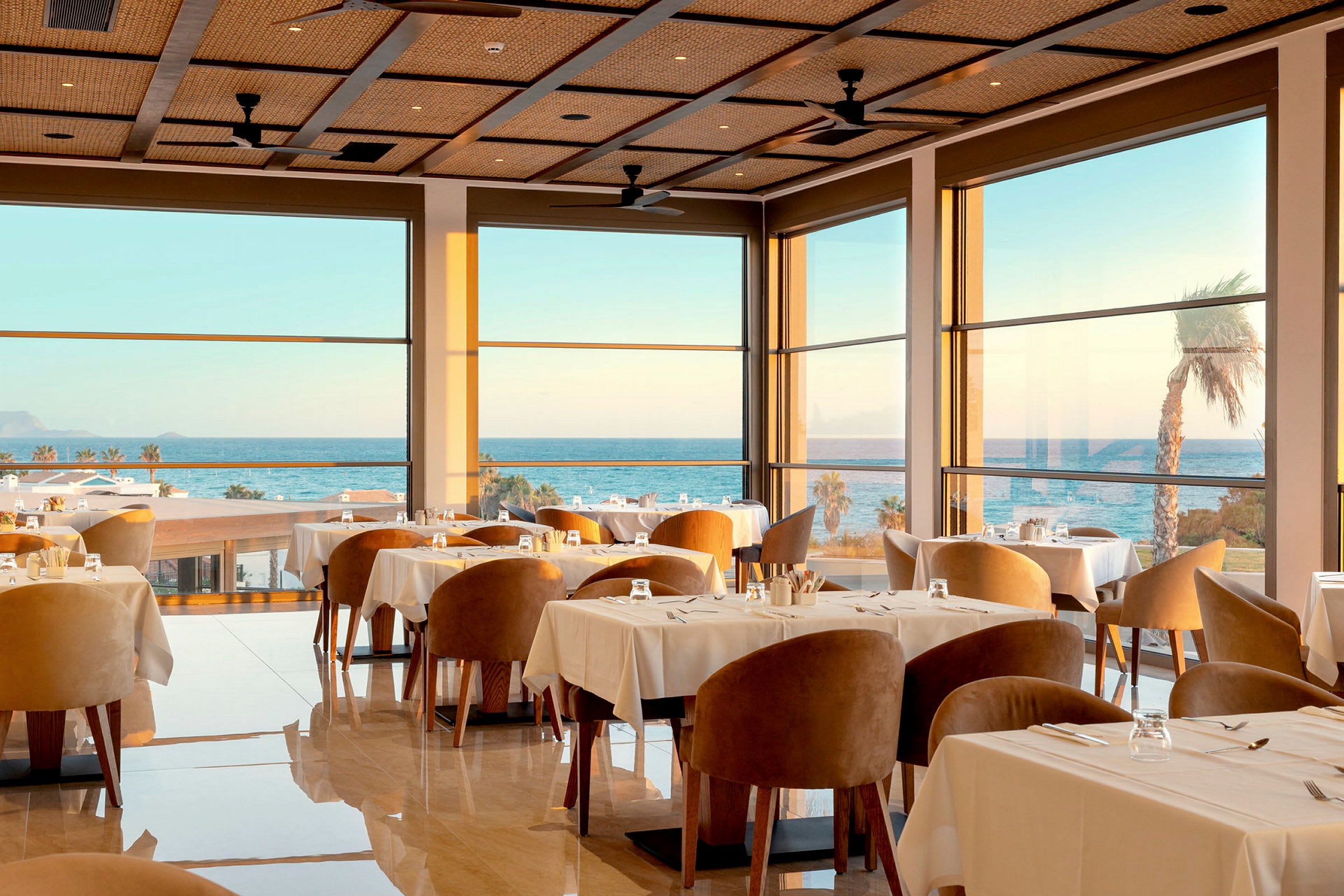 En elegant restaurant innendørs med store vinduer og havutsikt. (AI-generert tekst)