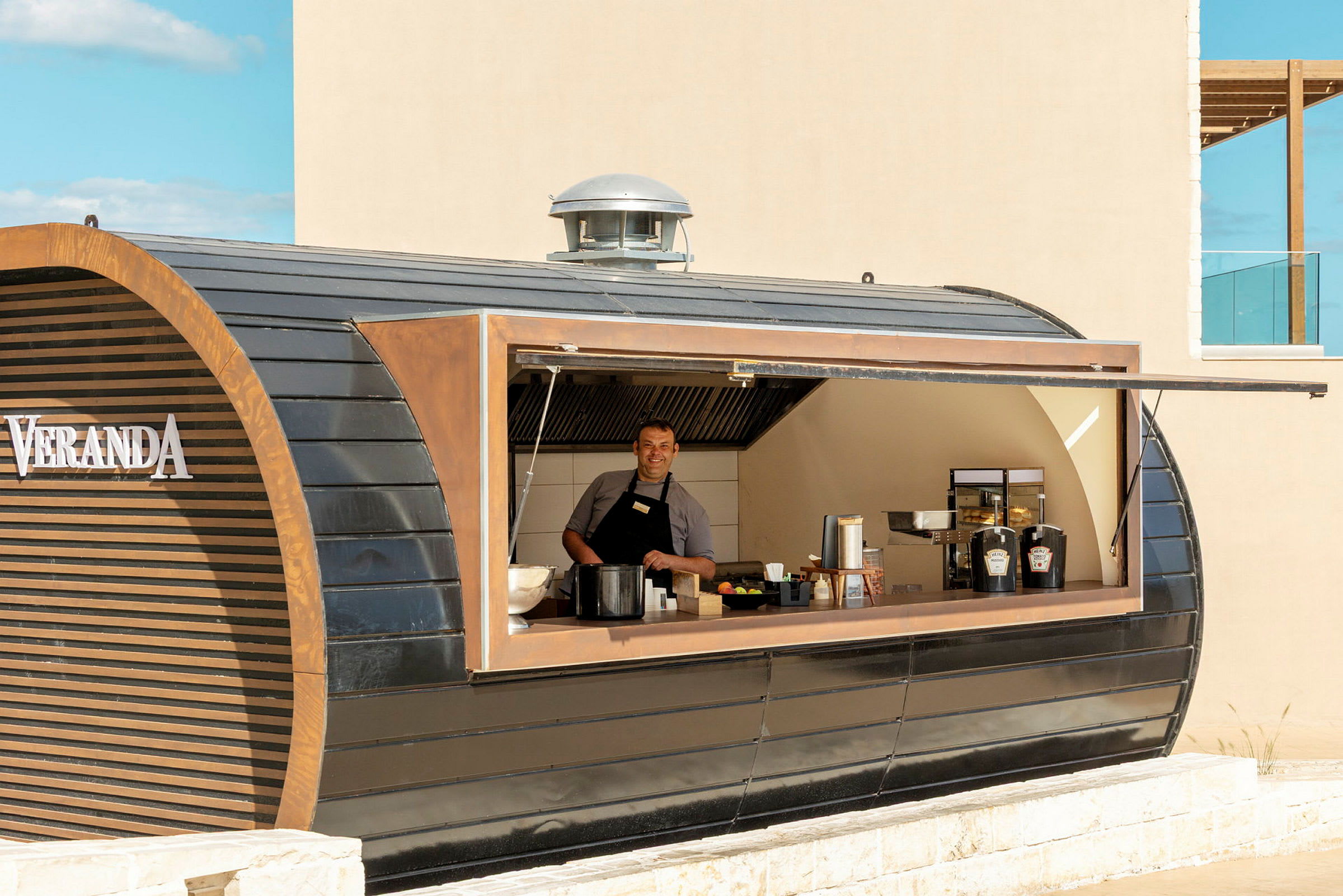 En person jobber i en serveringskiosk med moderne design som heter Veranda. (AI-generert tekst)
