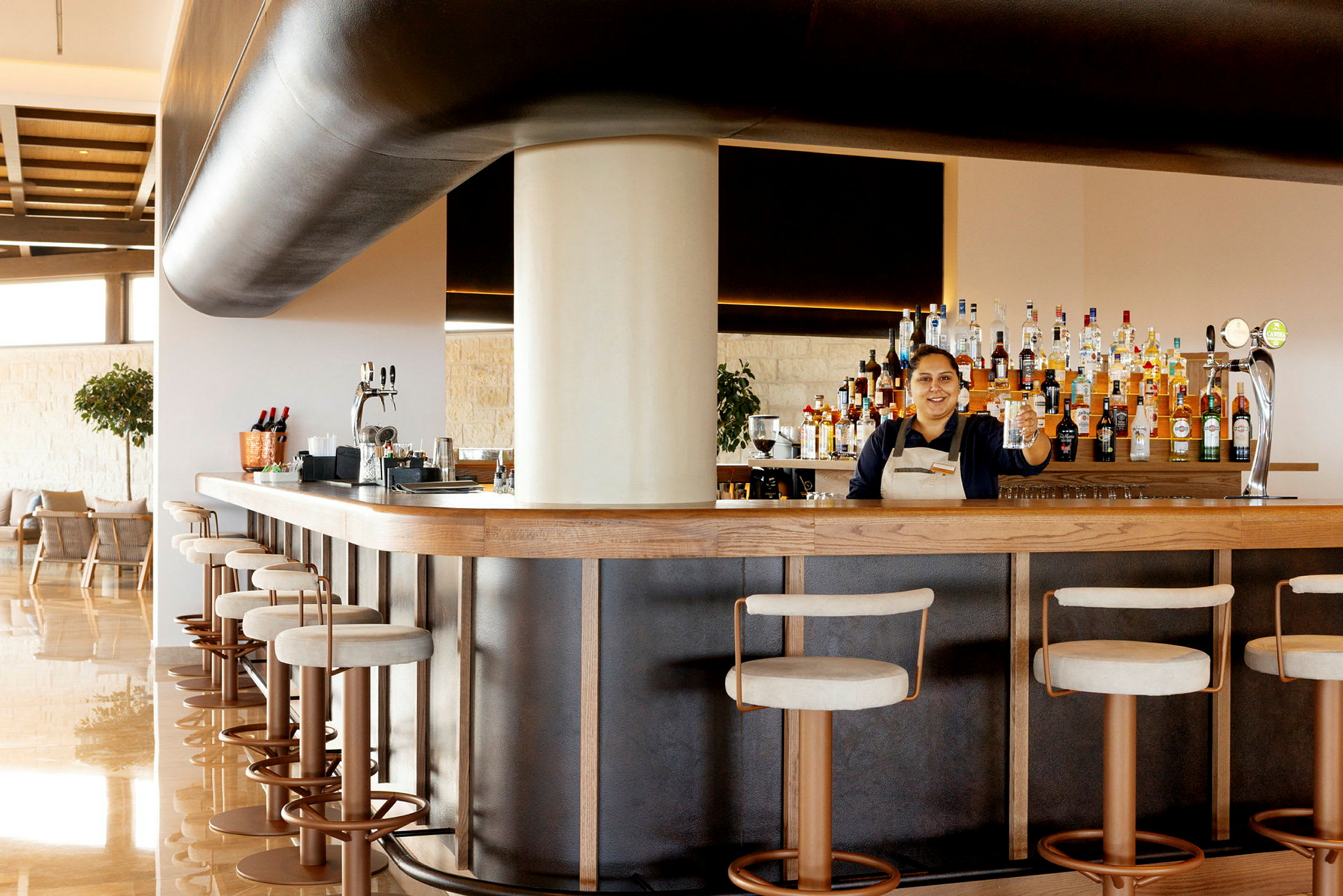 En bartender står bak en velutstyrt bar med barkrakker foran. (AI-generert tekst)