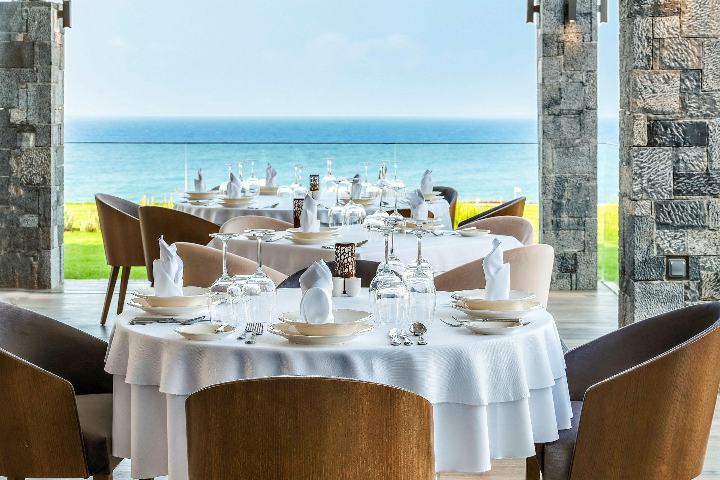 Bilde av en restaurant med dekkede bord, utsikt mot havet. (AI-generert tekst)