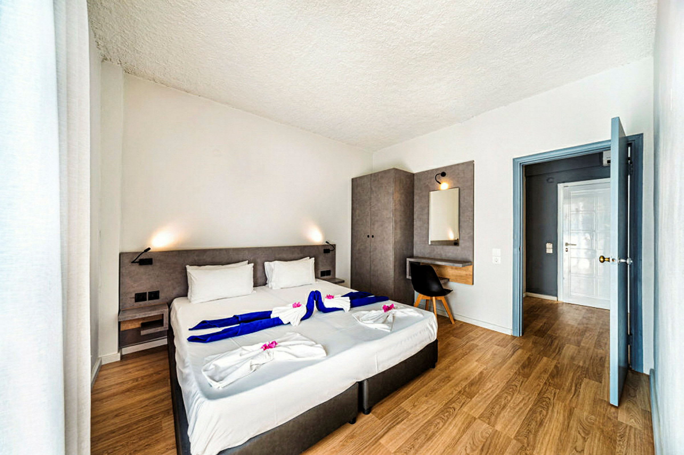 Moderne hotellrom med dobbeltseng, skrivebord og garderobe. (AI-generert tekst)