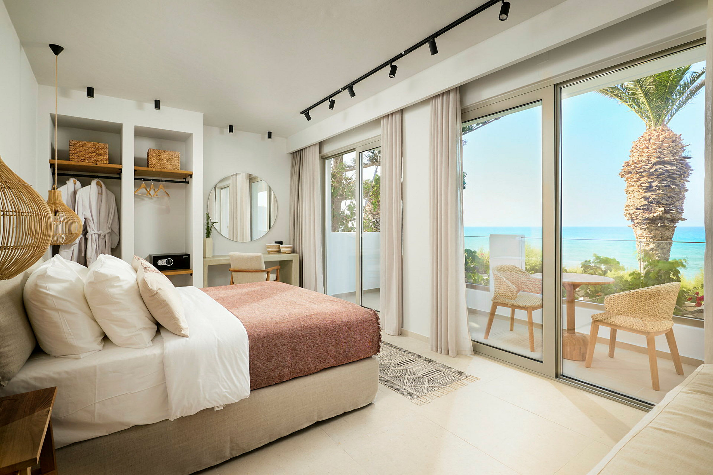Moderne hotellrom med seng, skrivebord, garderobe og balkong med havutsikt. (AI-generert tekst)