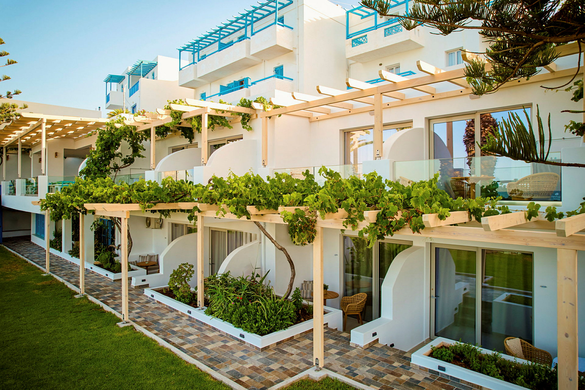 Hotellbygning med frodig terrasse og glassrekkverk. (AI-generert tekst)