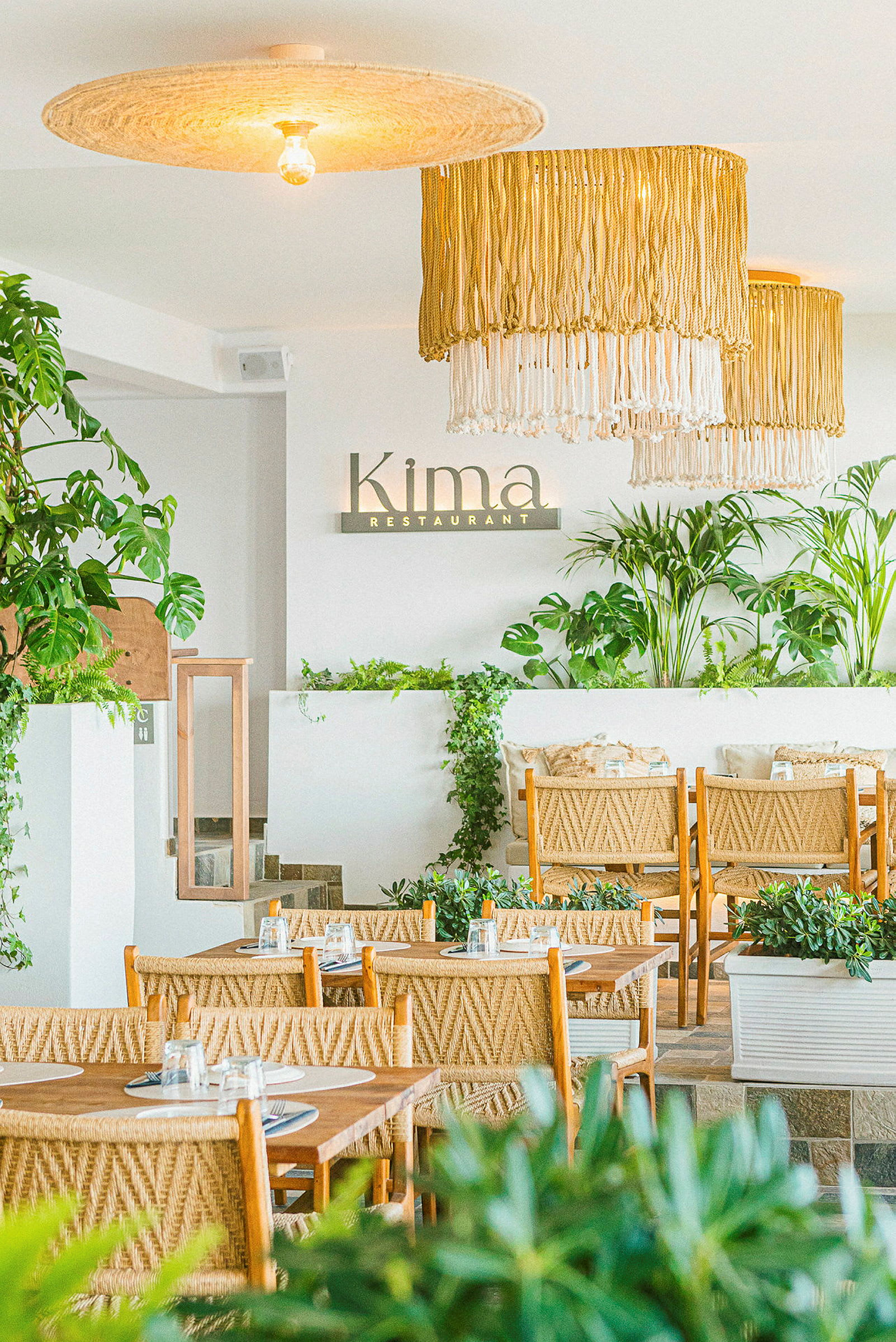 Bilde av interiøret på en restaurant med grønne planter og rottinginspirerte møbler. (AI-generert tekst)