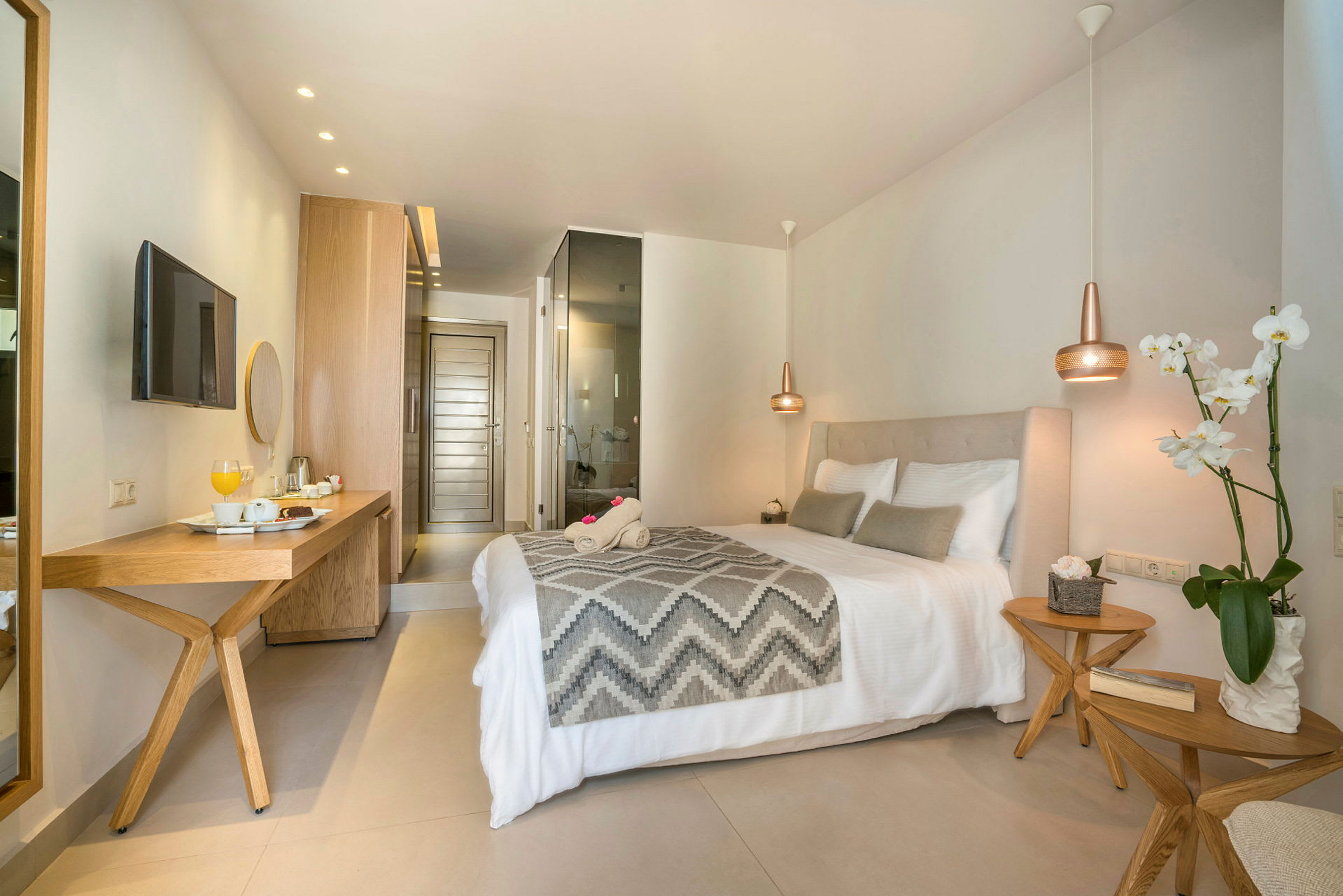 Et lyst hotellrom med en dobbeltseng, skrivebord og dekorative planter. (AI-generert tekst)