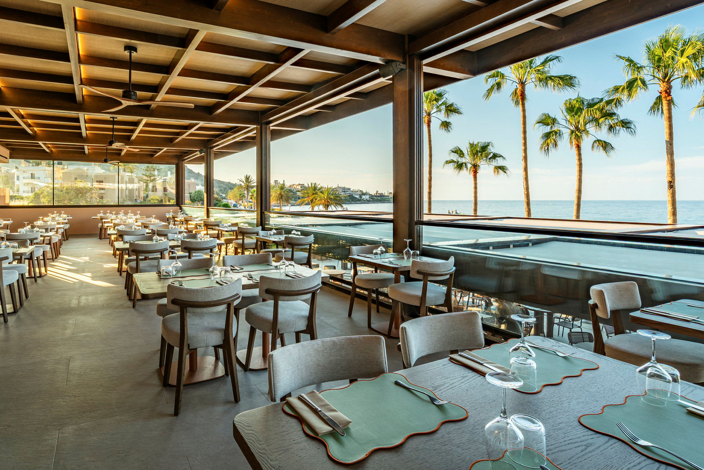 Restaurant med sitteplasser, utsikt mot havet og palmer. (AI-generert tekst)