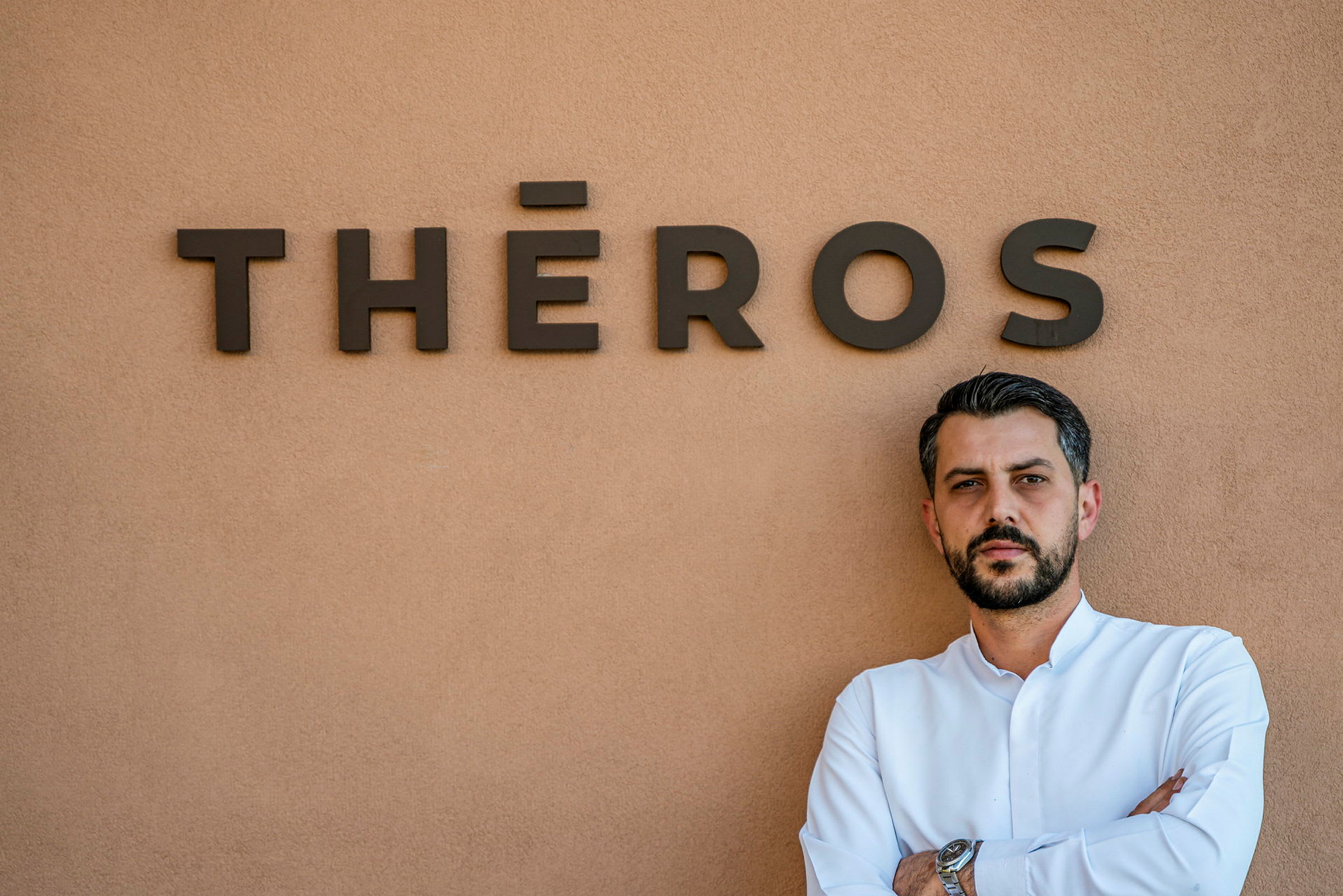Mann foran en vegg med teksten "THÉROS". (AI-generert tekst)