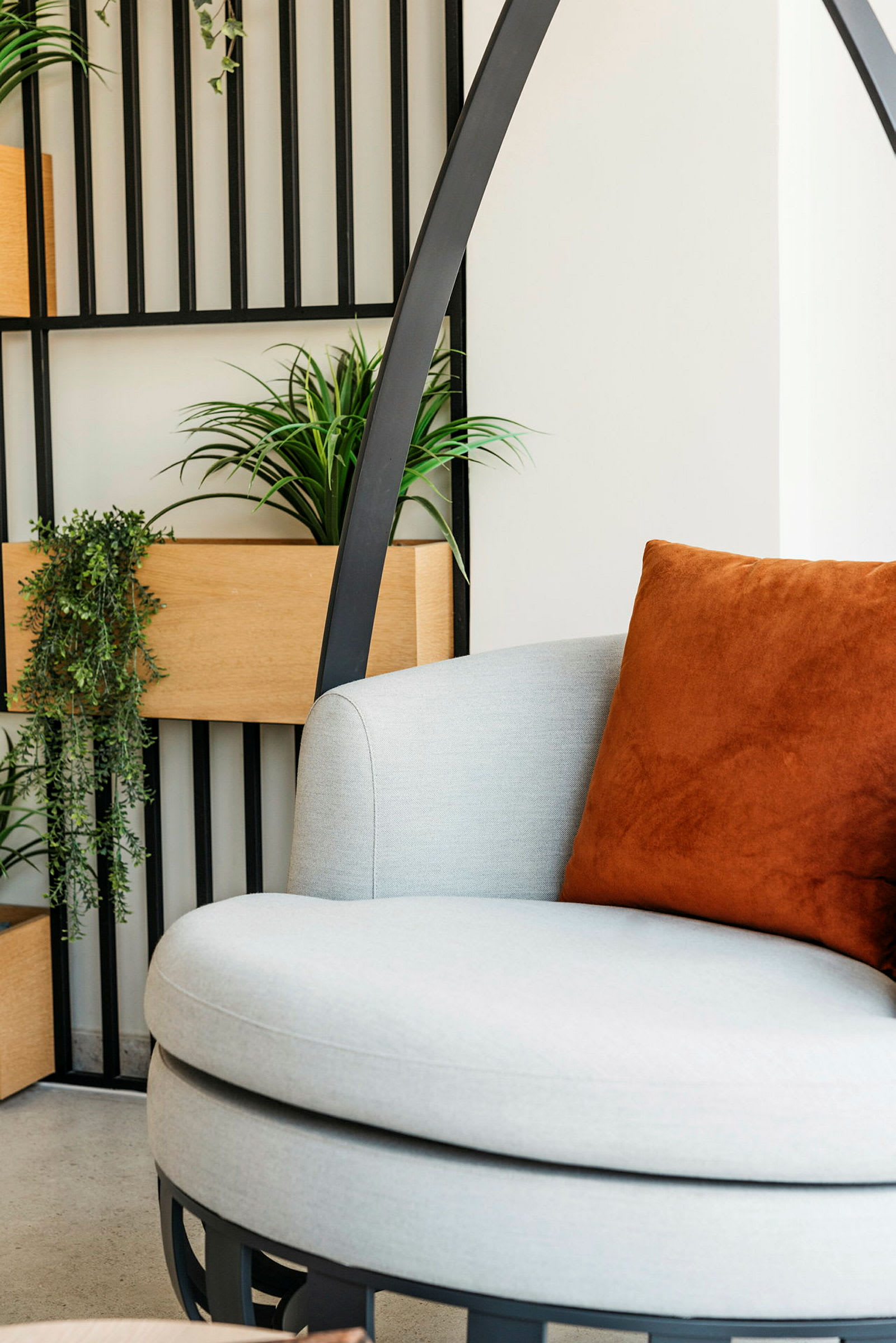 En moderne stol med en oransje pute og grønne planter i et stilrent miljø. (AI-generert tekst)