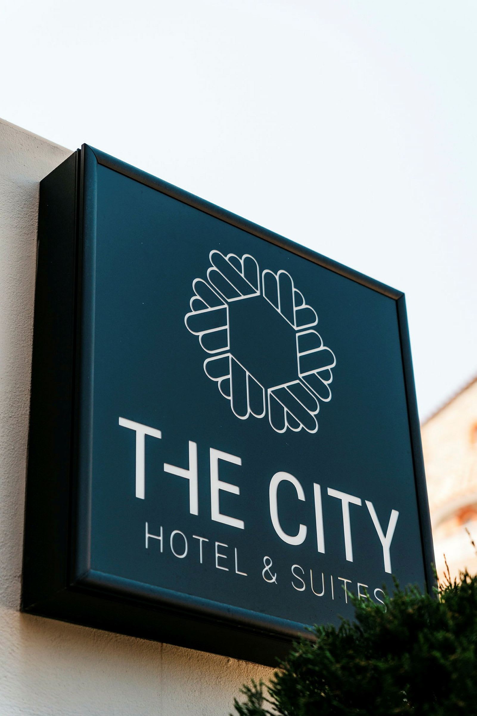 Skilt for "The City Hotel & Suites" mot lys bakgrunn. (AI-generert tekst)