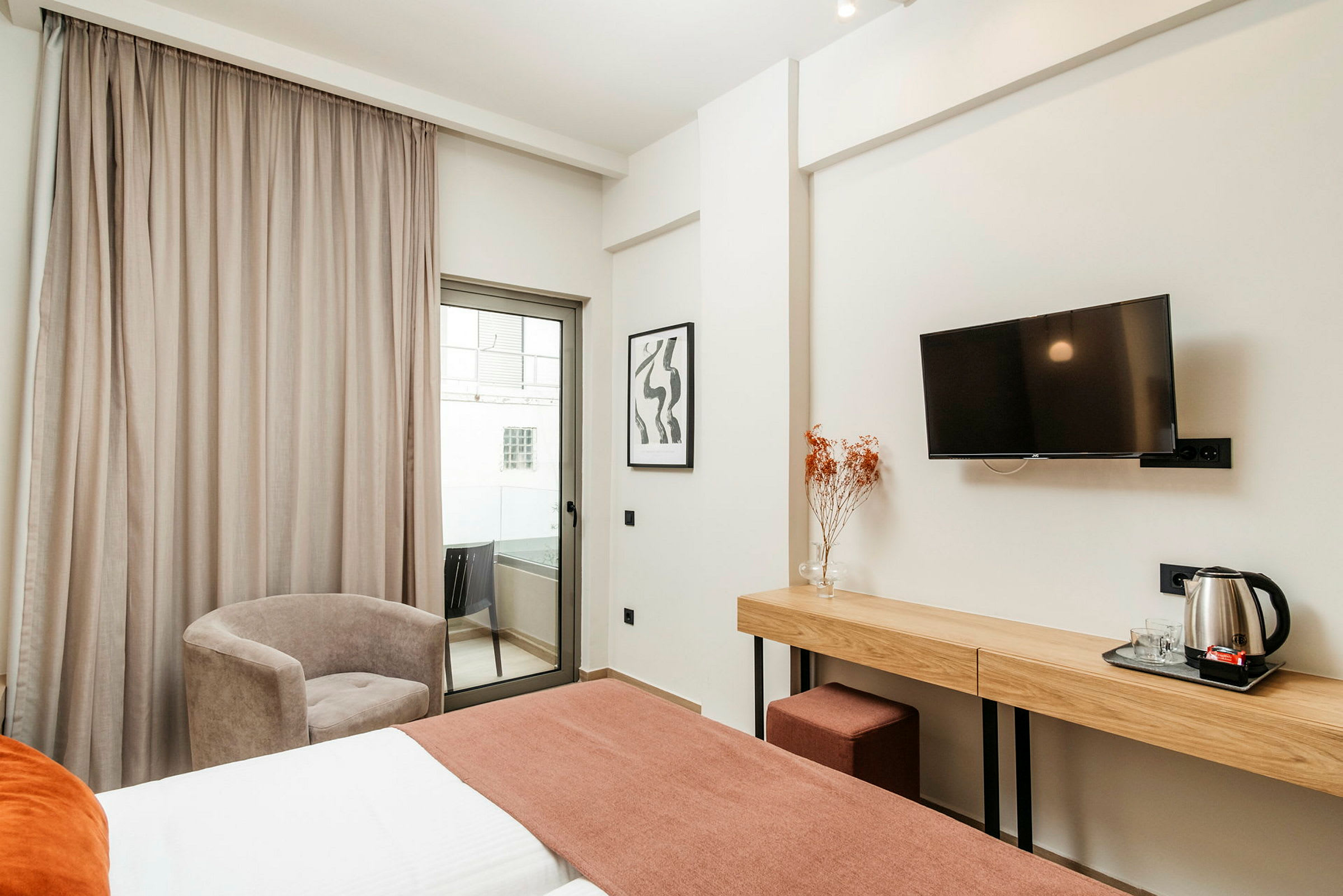 Et hotellrom med seng, skrivebord, stol og balkong. (AI-generert tekst)
