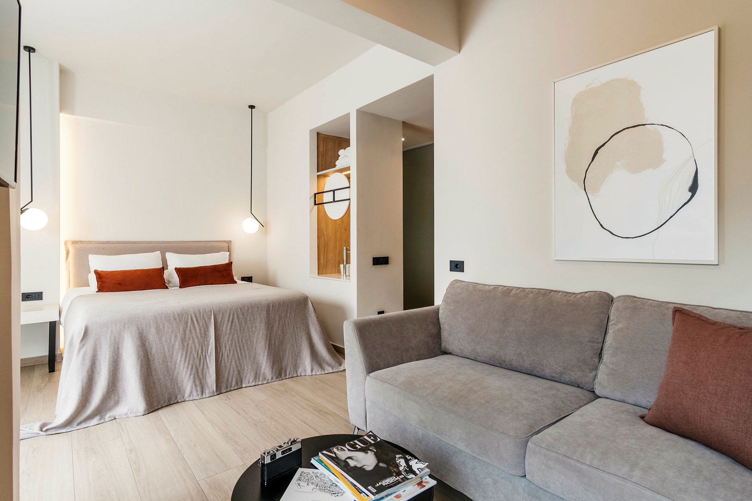 Et moderne hotellrom med en stor seng, sofa og minimalistisk innredning. (AI-generert tekst)