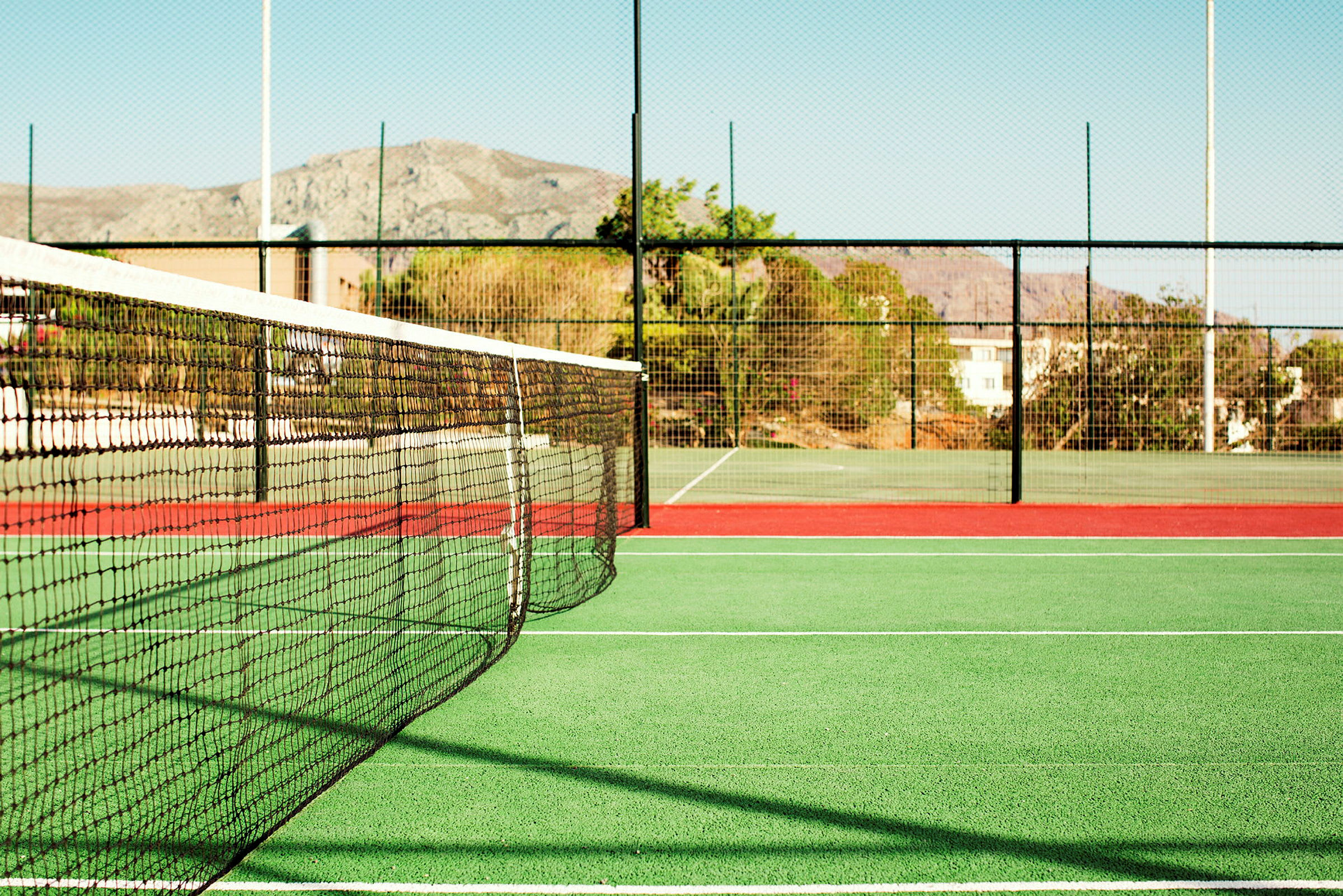 En tennisbane med nett og gjerde. (AI-generert tekst)