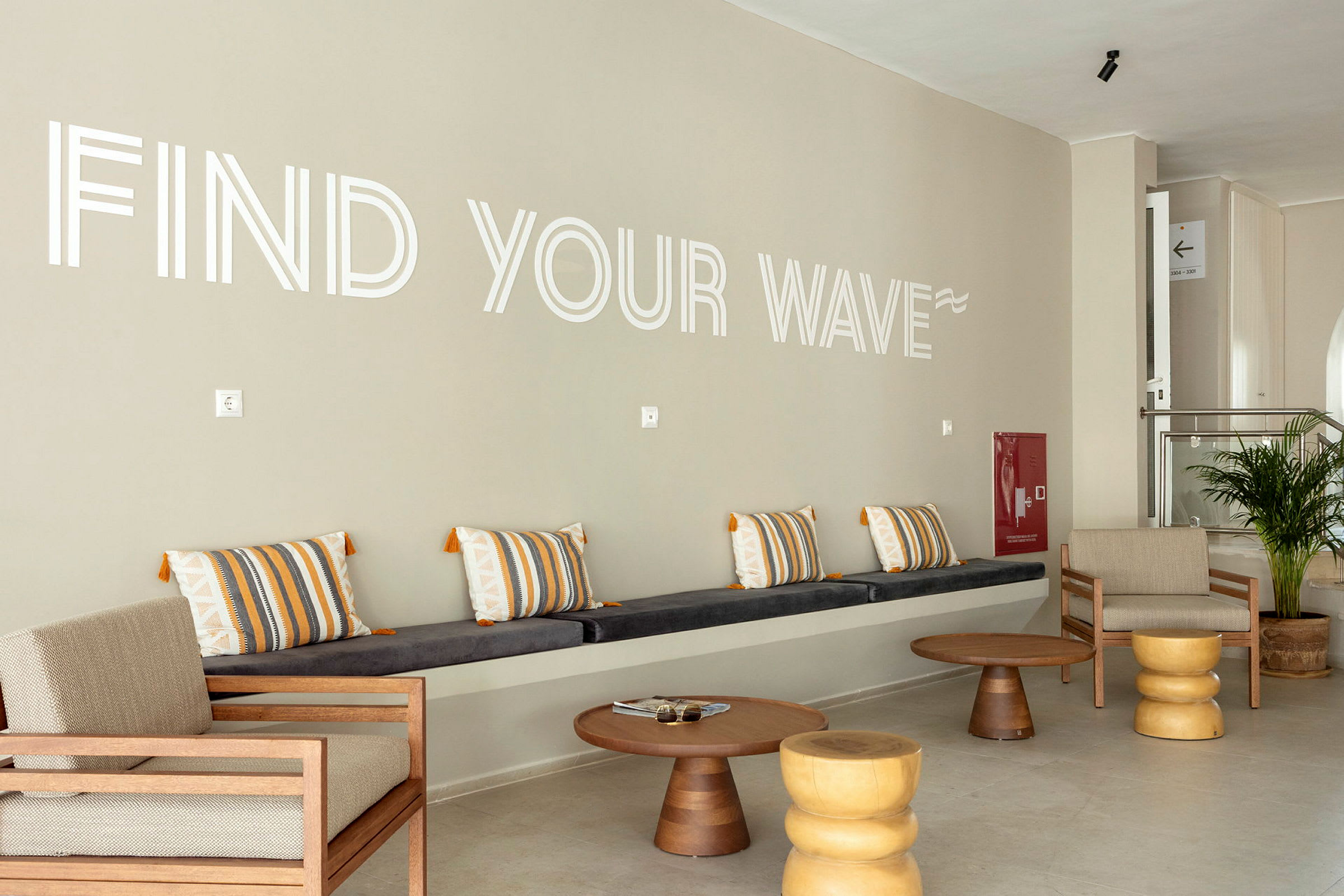 En lounge med sitteplasser og teksten 'Find Your Wave' på veggen. (AI-generert tekst)
