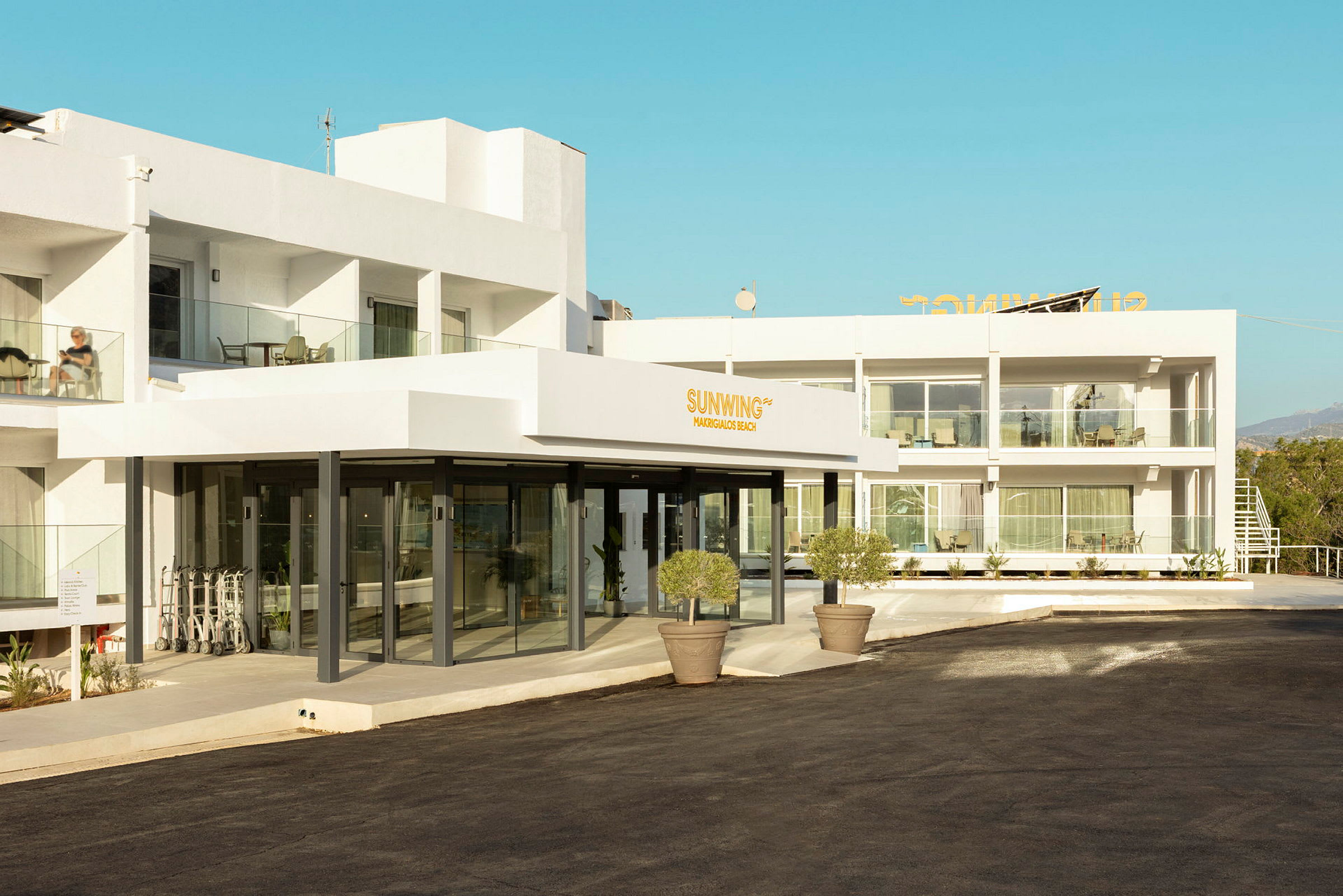 Fasade av et moderne hotellkompleks med hvite vegger og gangvei foran. (AI-generert tekst)
