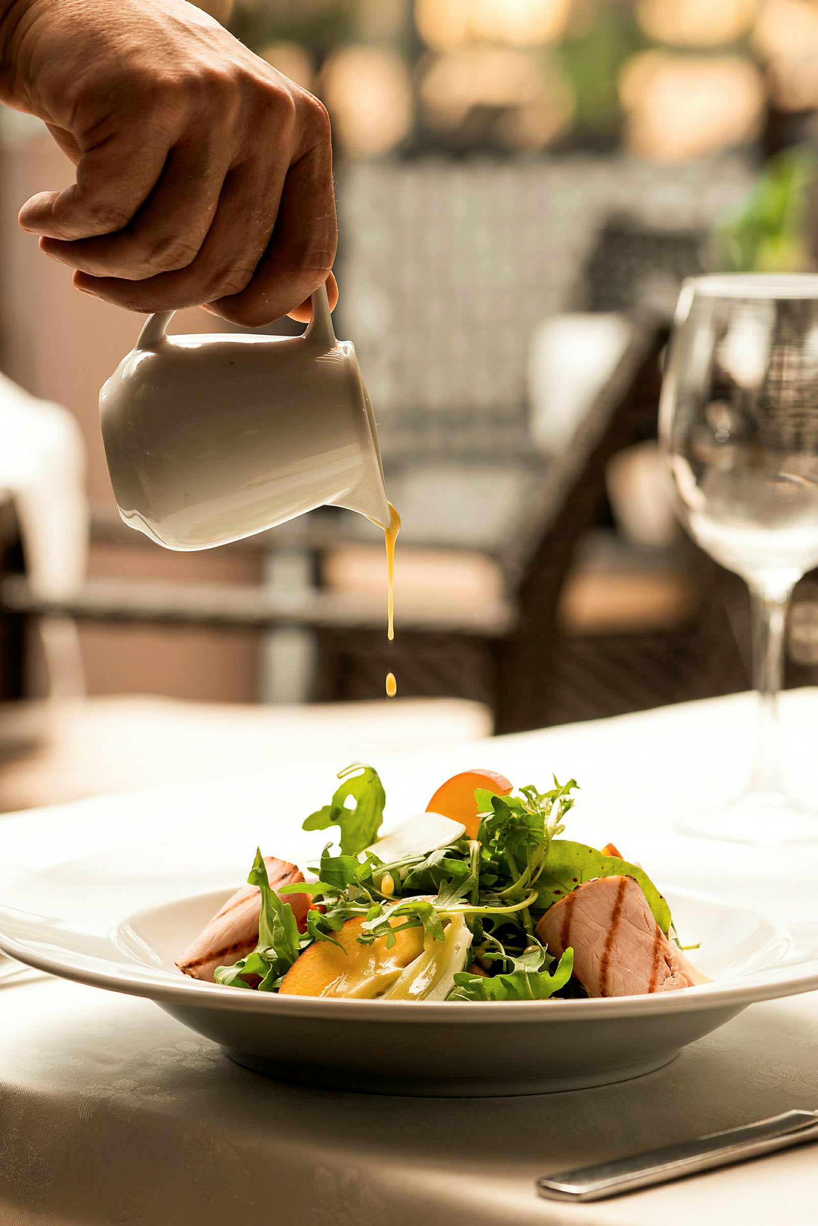 Hånd som heller dressing over en salat. (AI-generert tekst)