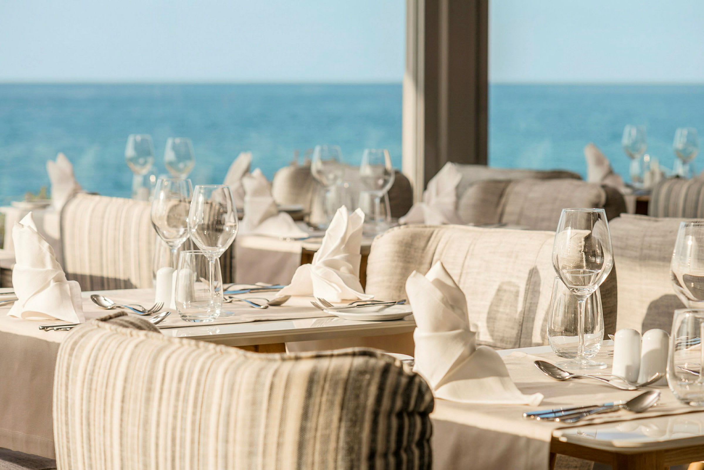 Restaurant med famlagte bord og utsikt over havet. (AI-generert tekst)