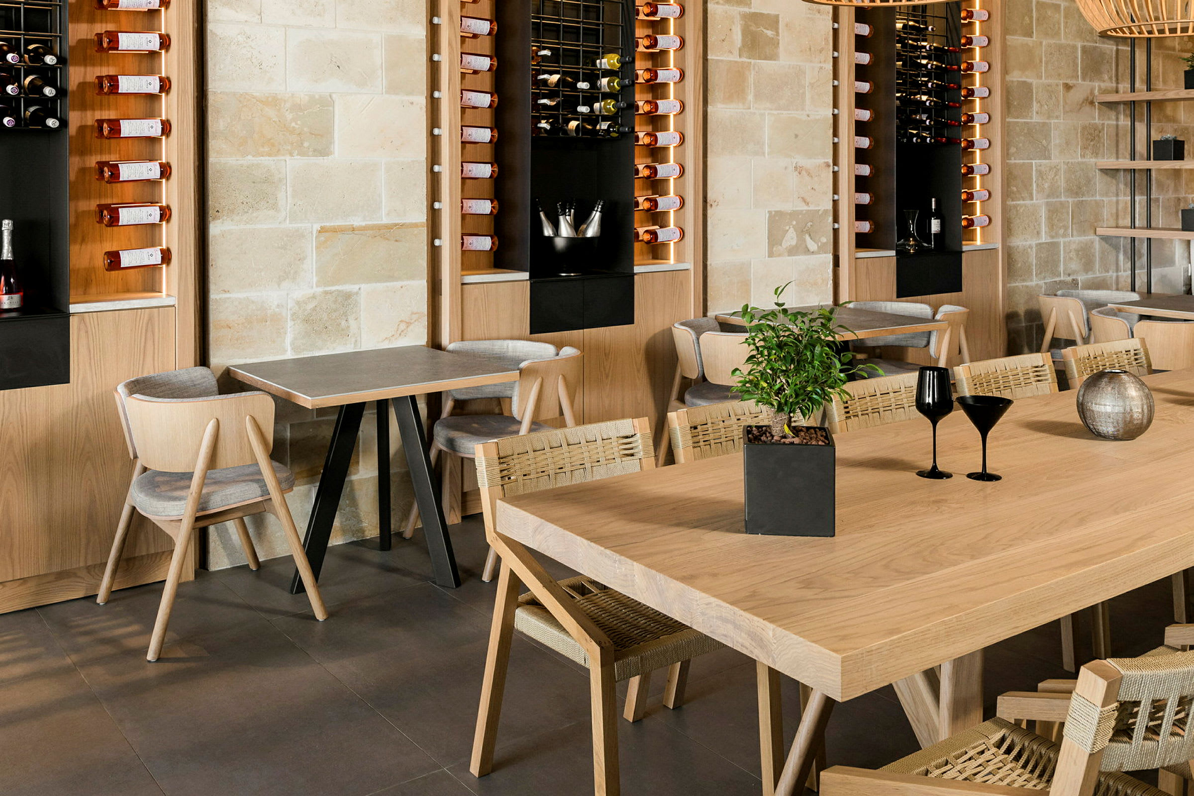 En moderne restaurant med trebord og stoler samt veggoppbevaring for vinflasker. (AI-generert tekst)