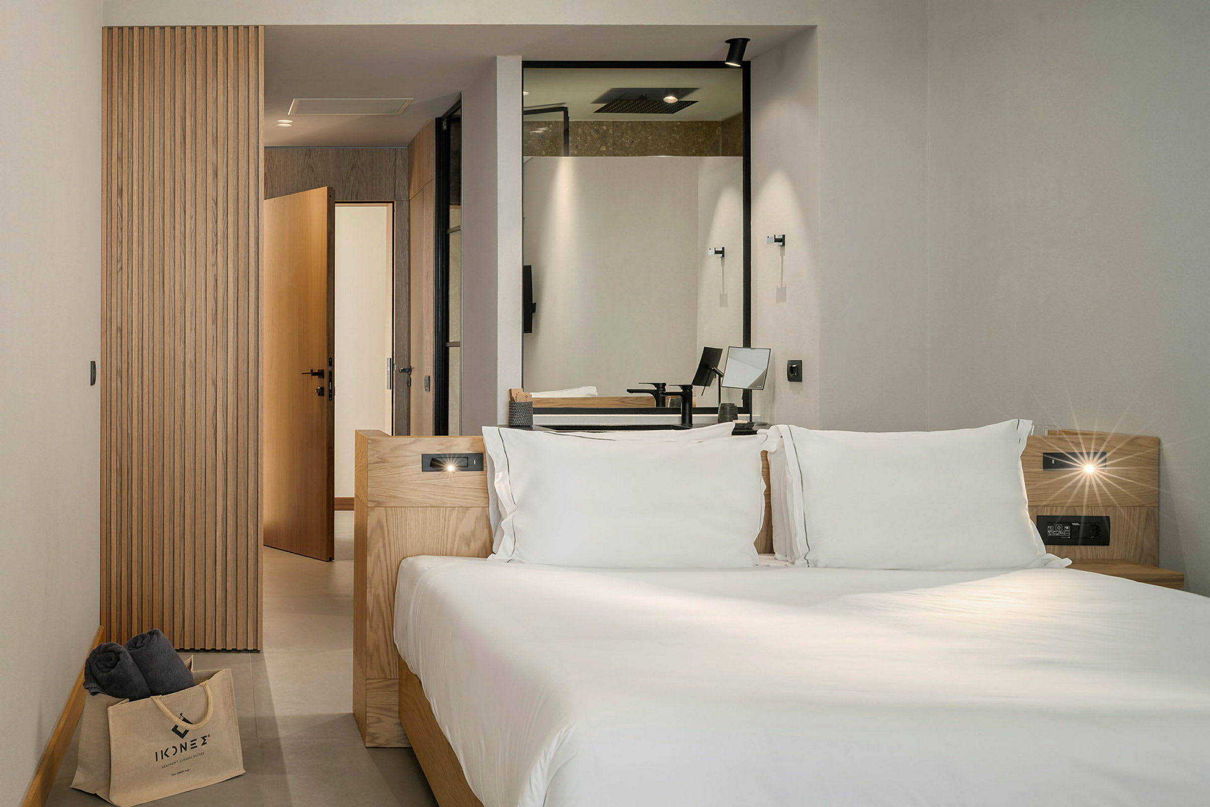 Moderne hotellrom med en dobbeltseng, hovedsakelig innredet med tredetaljer og med innsyn mot baderom. (AI-generert tekst)