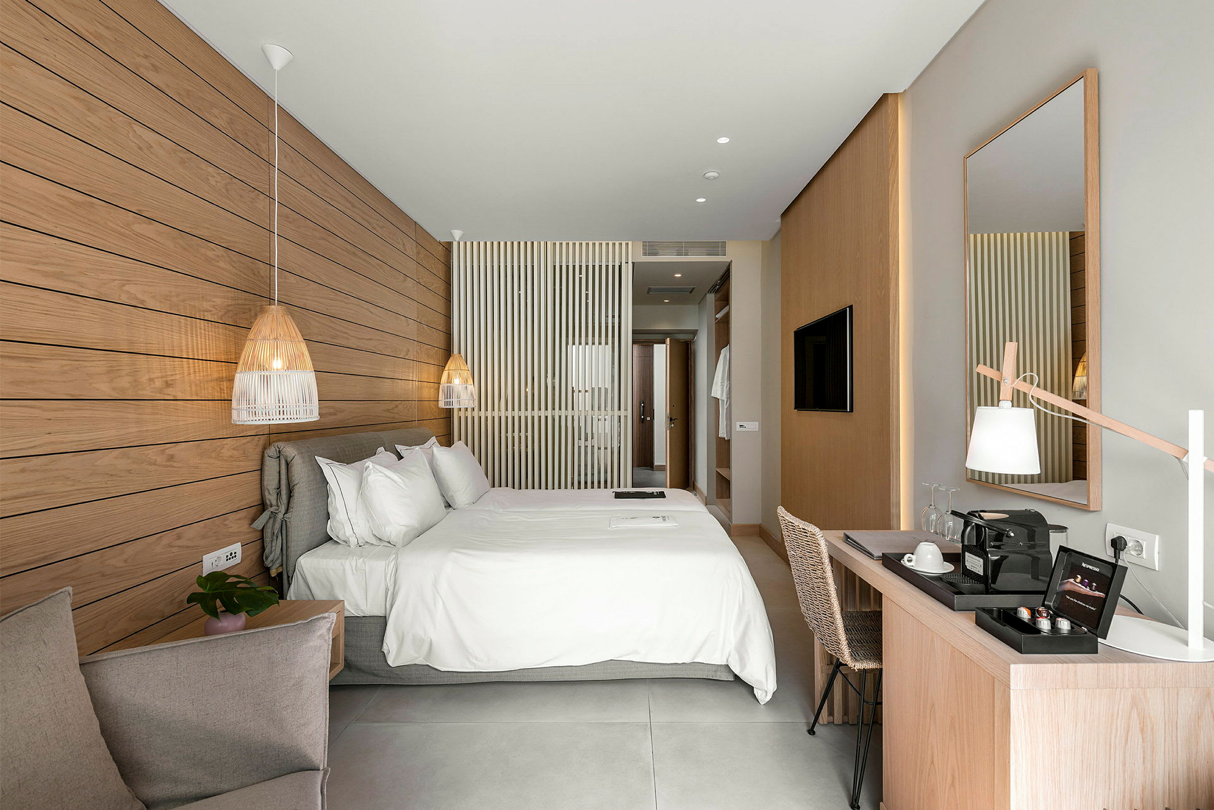 Et lyst og moderne hotellrom med en stor dobbeltseng, et skrivebord og en dekorativ marmorpanel på veggen. (AI-generert tekst)