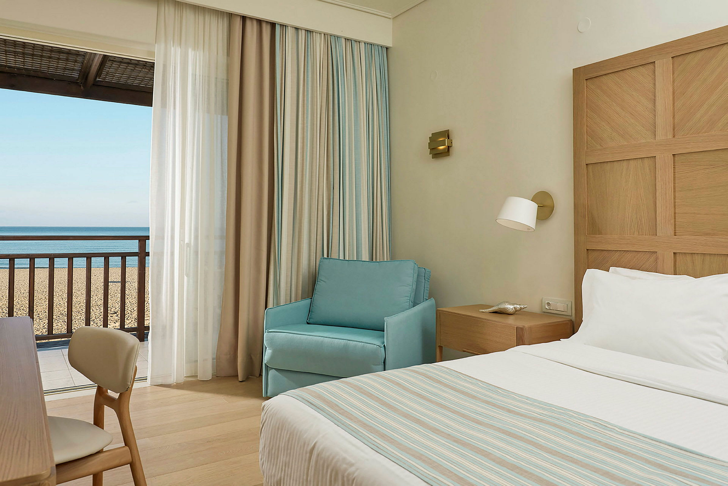 Hotellrom med utsikt mot sandstrand og hav. (AI-generert tekst)