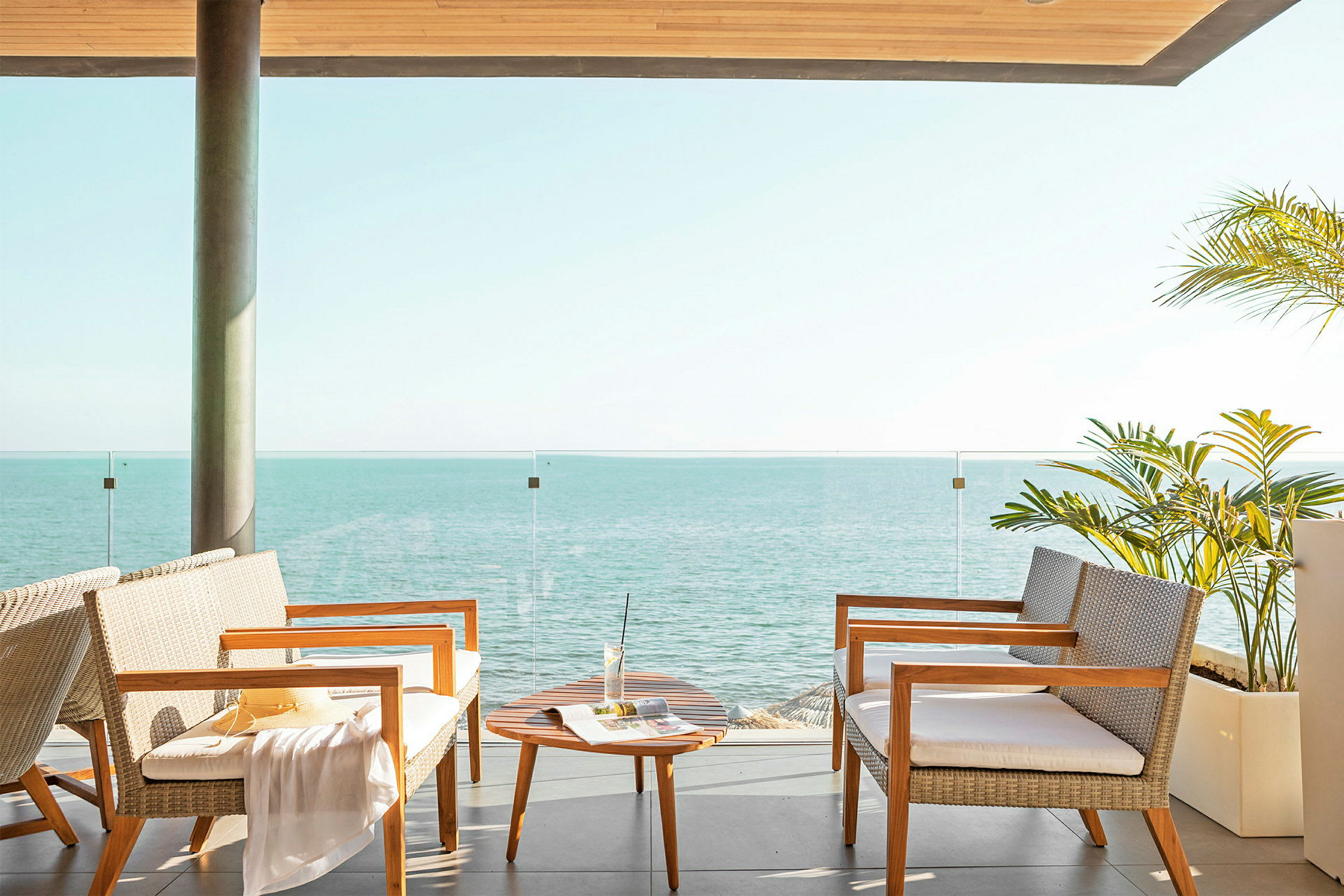 Terrasse med sittemøbler, et lite bord og utsikt over havet. (AI-generert tekst)
